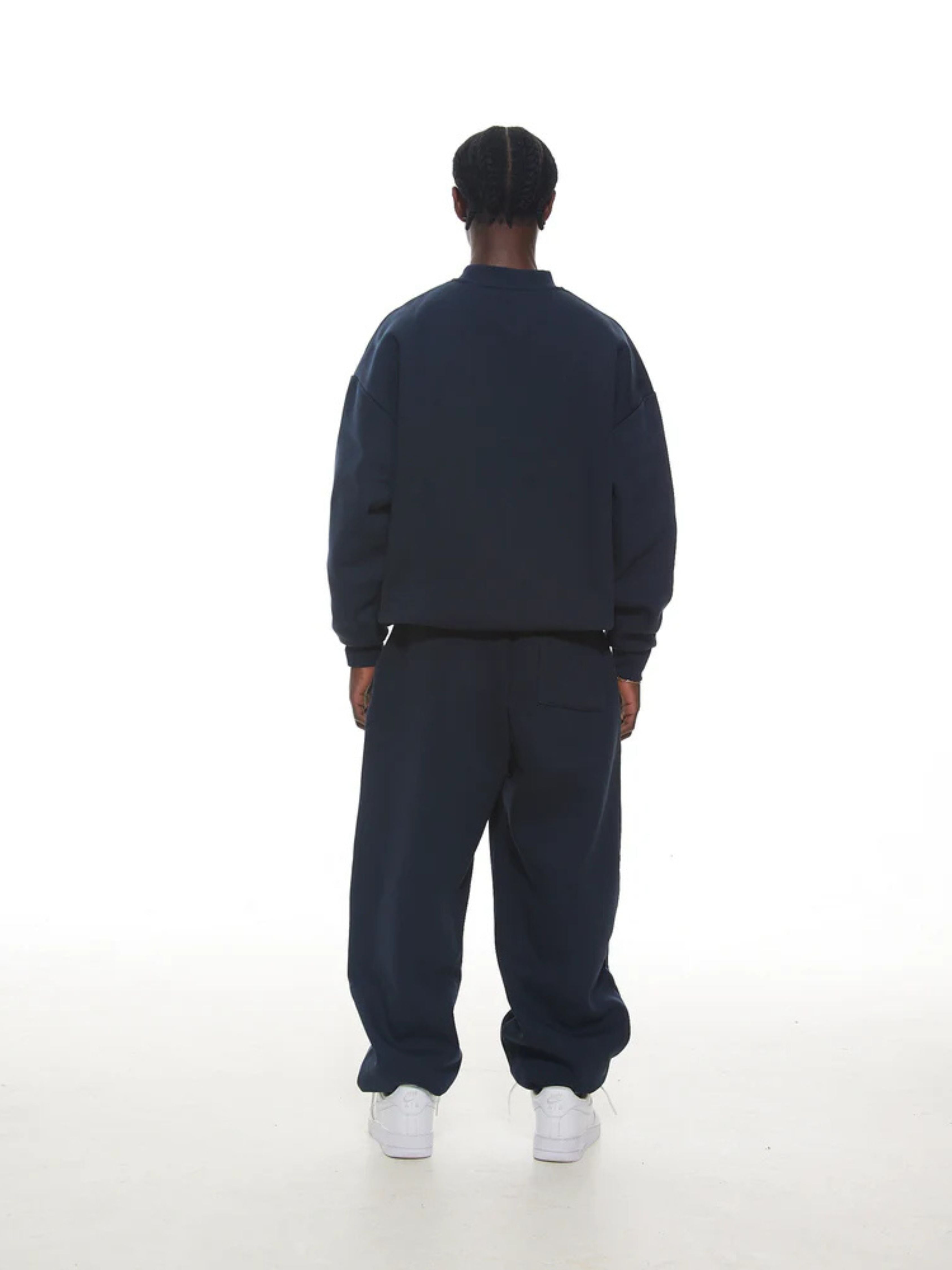 Person wearing a navy tracksuit on a white background