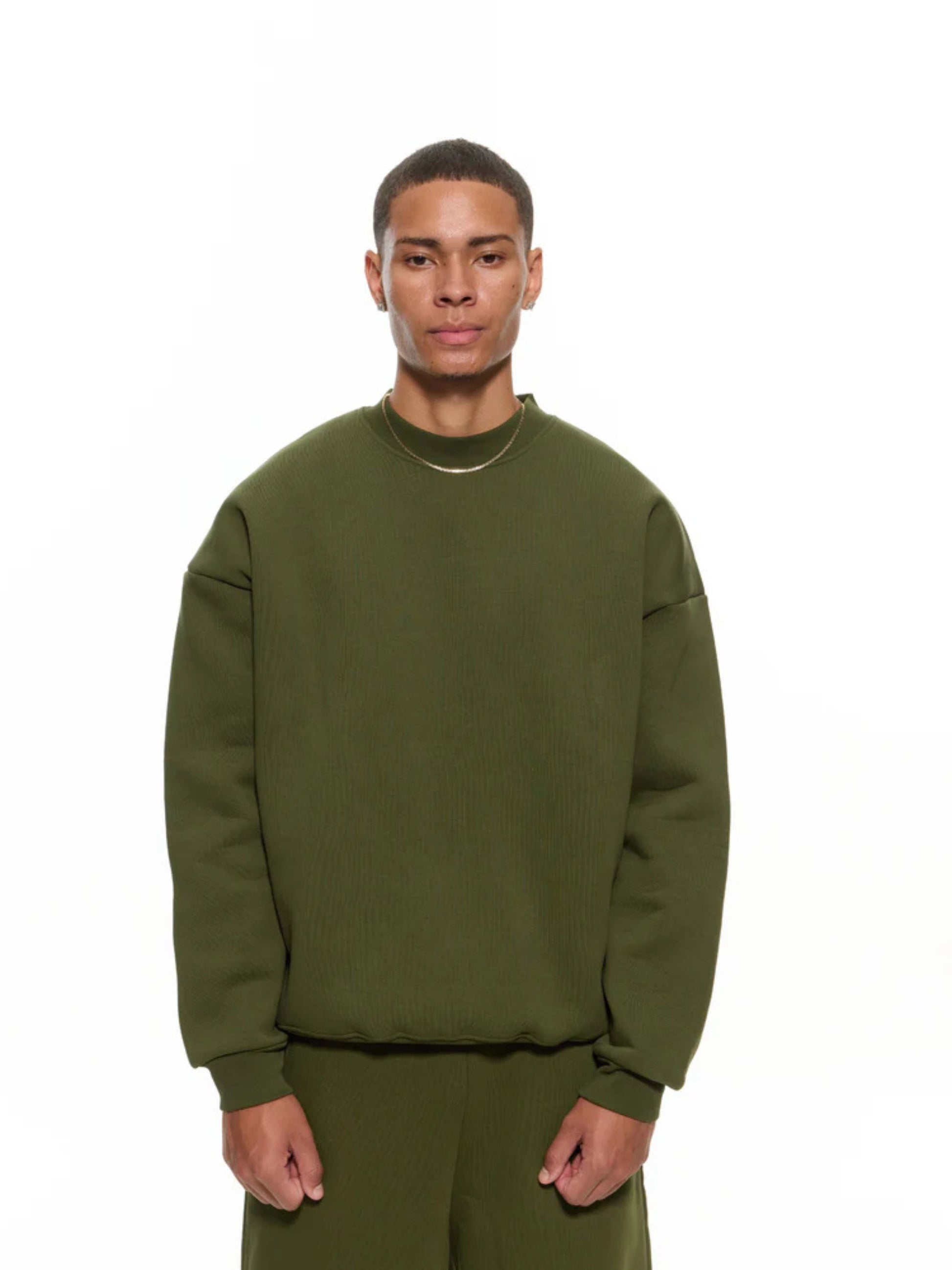 Person wearing a green sweatshirt and pants on a white background