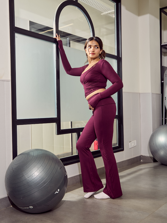 Woman in a purple pilates outfit standing next to exercise balls in a room with large mirrors.