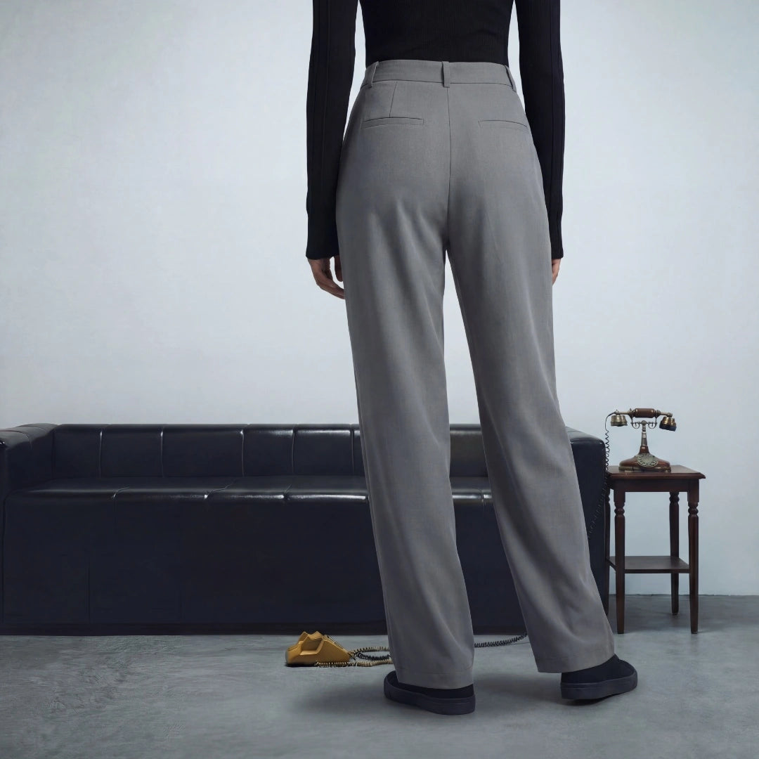 Person wearing gray pants standing in a minimalistic room with a sofa and small table.