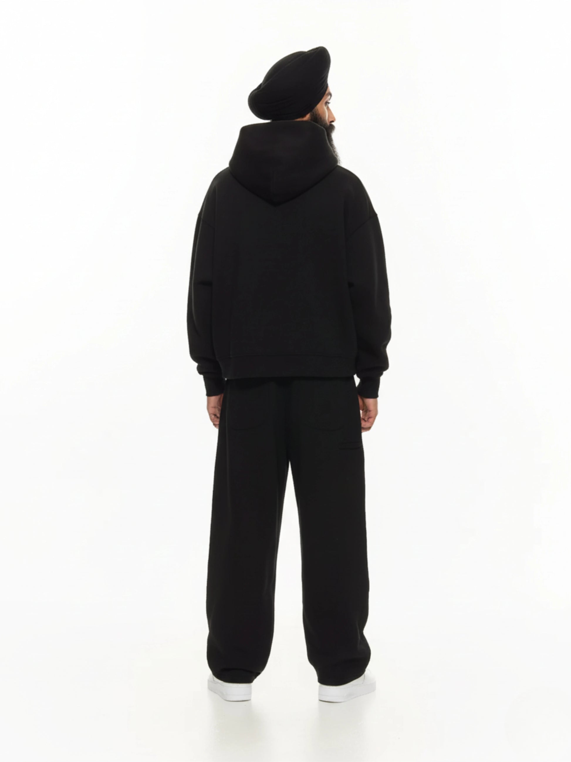 Person wearing a black hoodie and pants on a white background