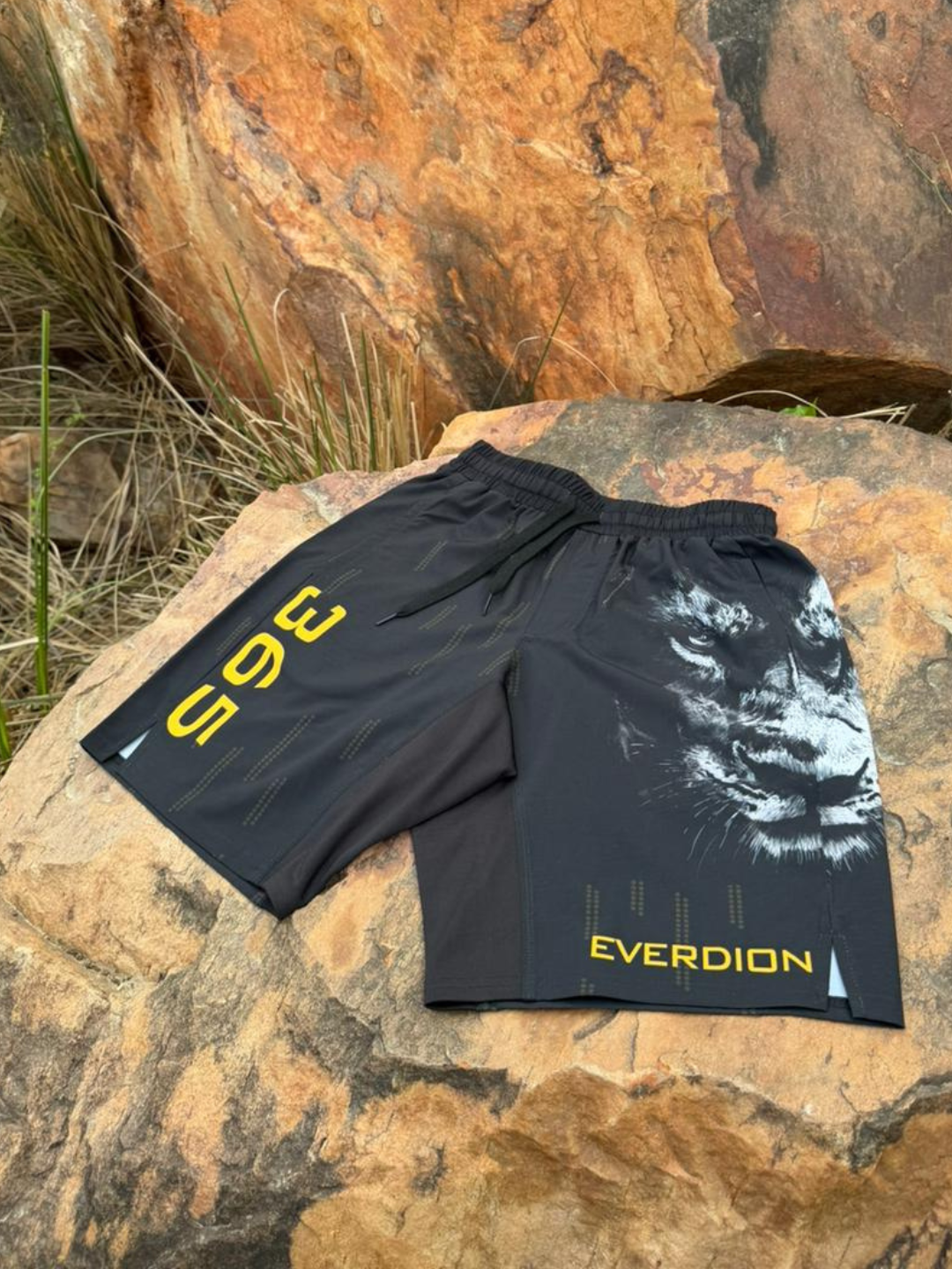 Black shorts with '365' and 'Everdion' branding on a rocky surface