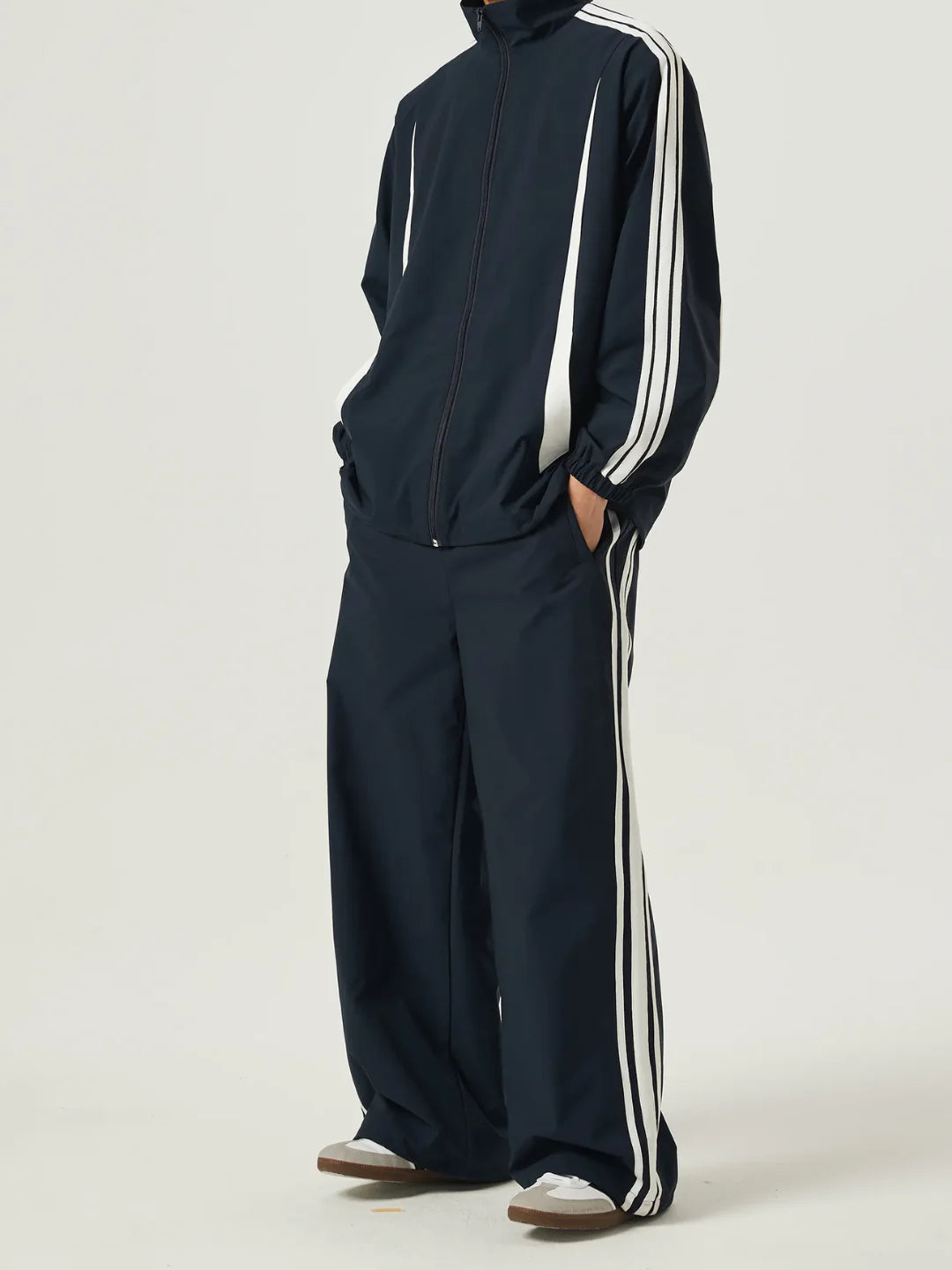 Navy tracksuit with white stripes on a plain background