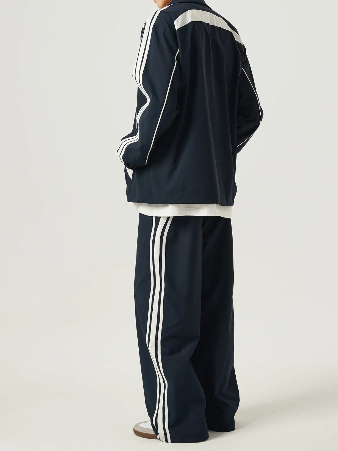 navy blue race track pants with white stripes on the side and an elasticated waistband with a drawstring