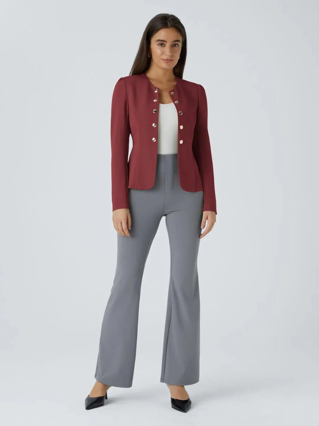 Woman wearing a maroon buisness jacket with gold buttons on a light gray background