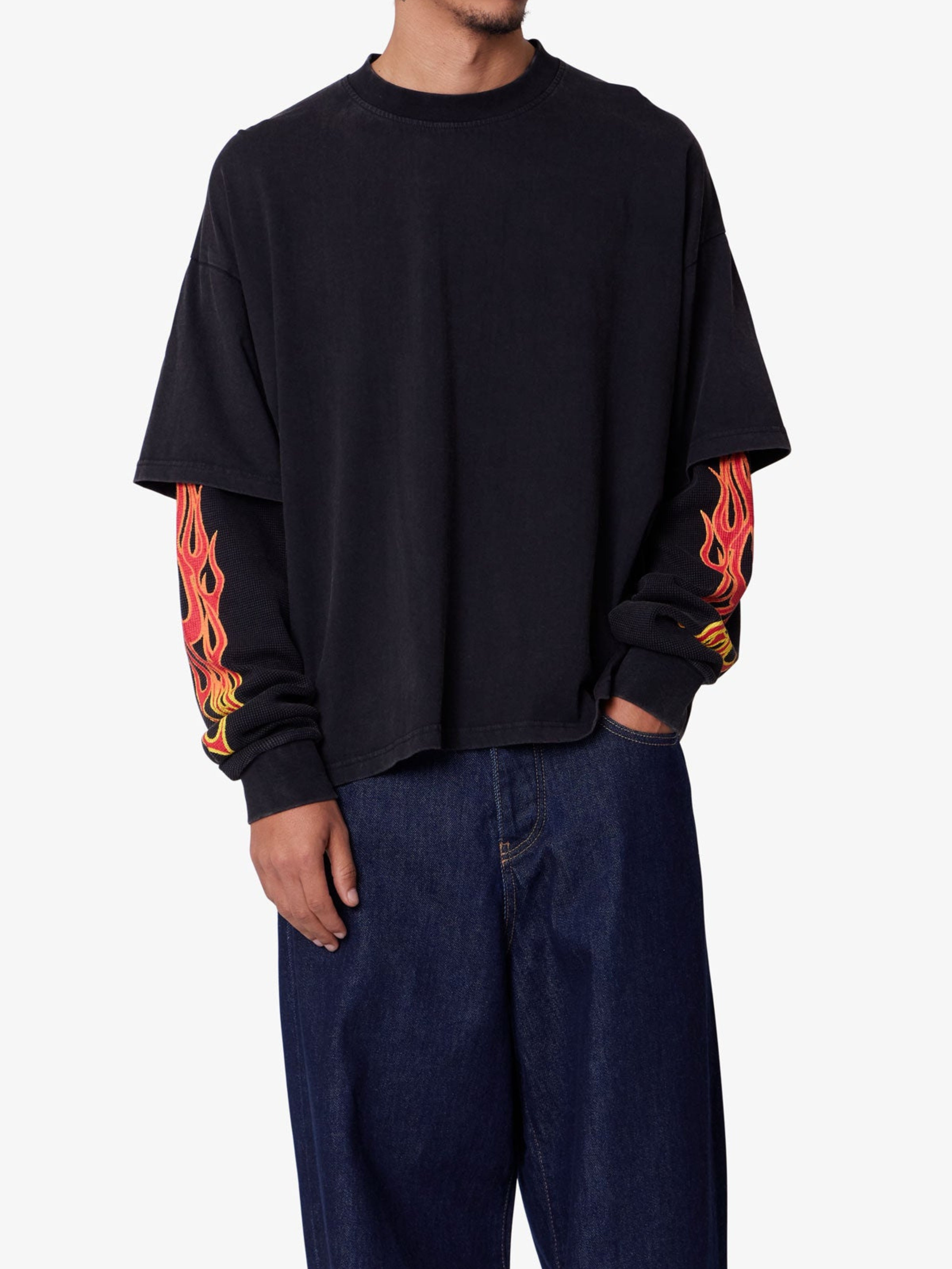 Person wearing a black sweatshirt with flame designs on the sleeves against a white background