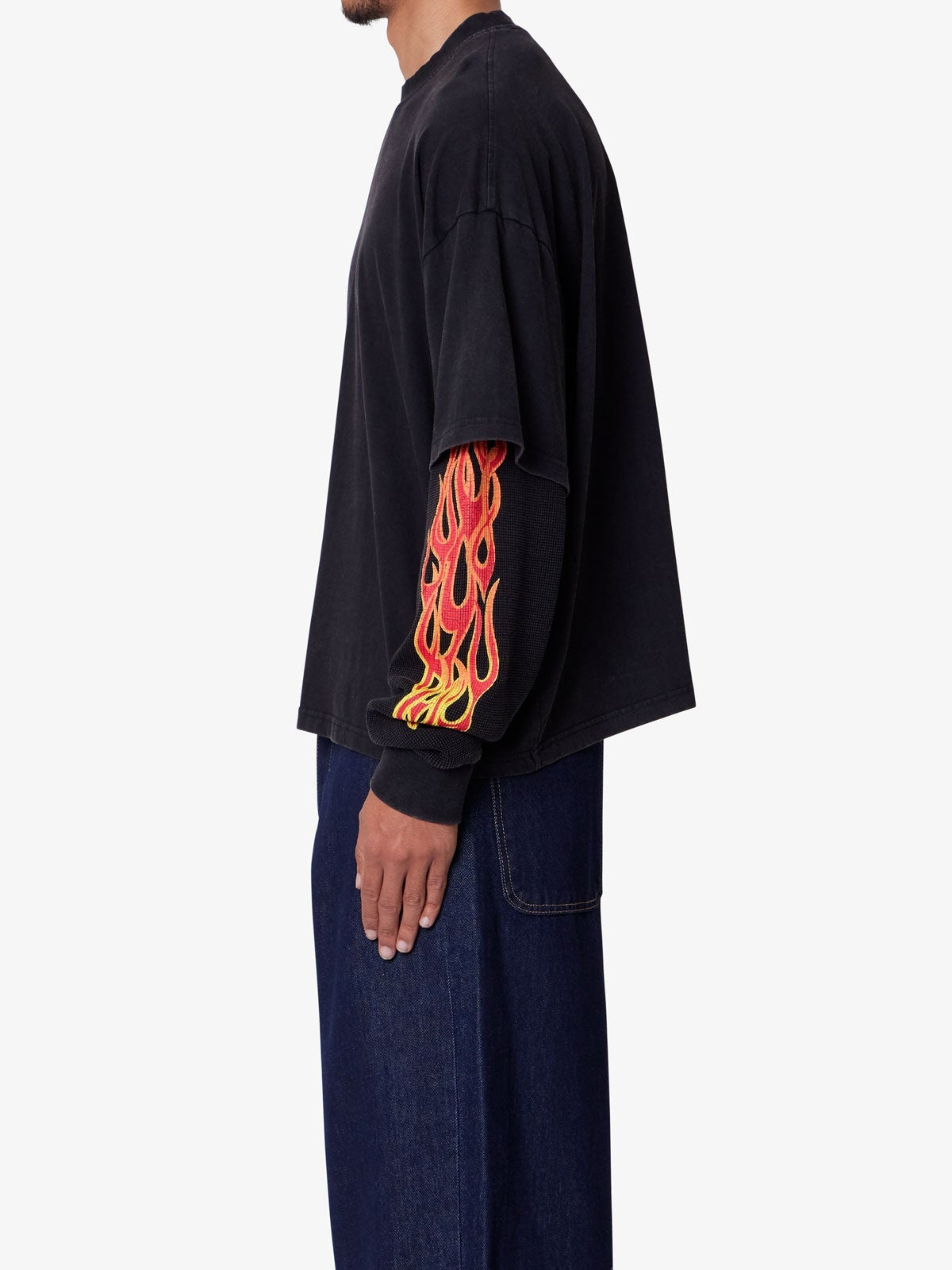 Person wearing a black long-sleeve shirt with flame design on a white background