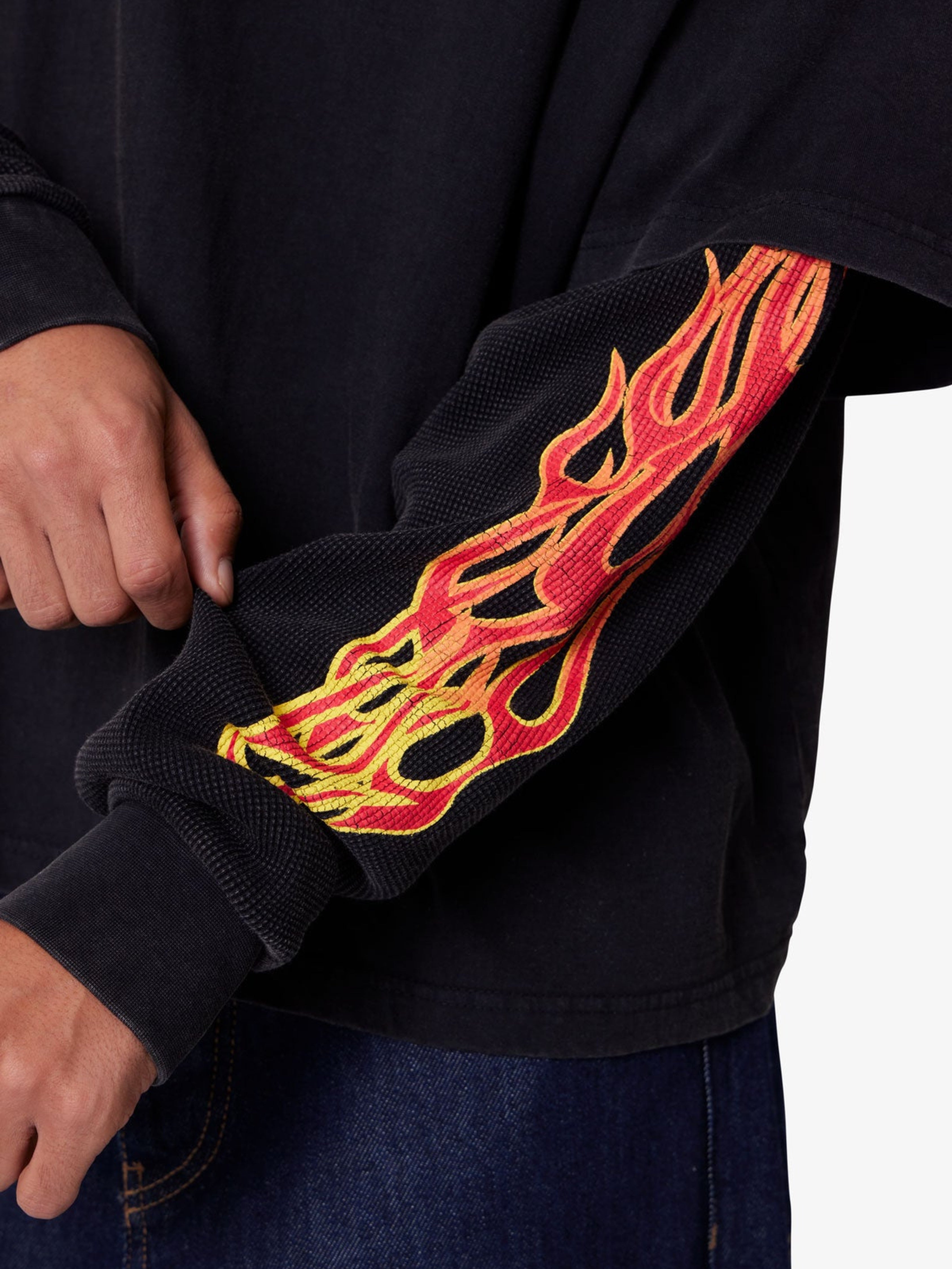Black sweatshirt with red and yellow flame design on sleeve against a white background
