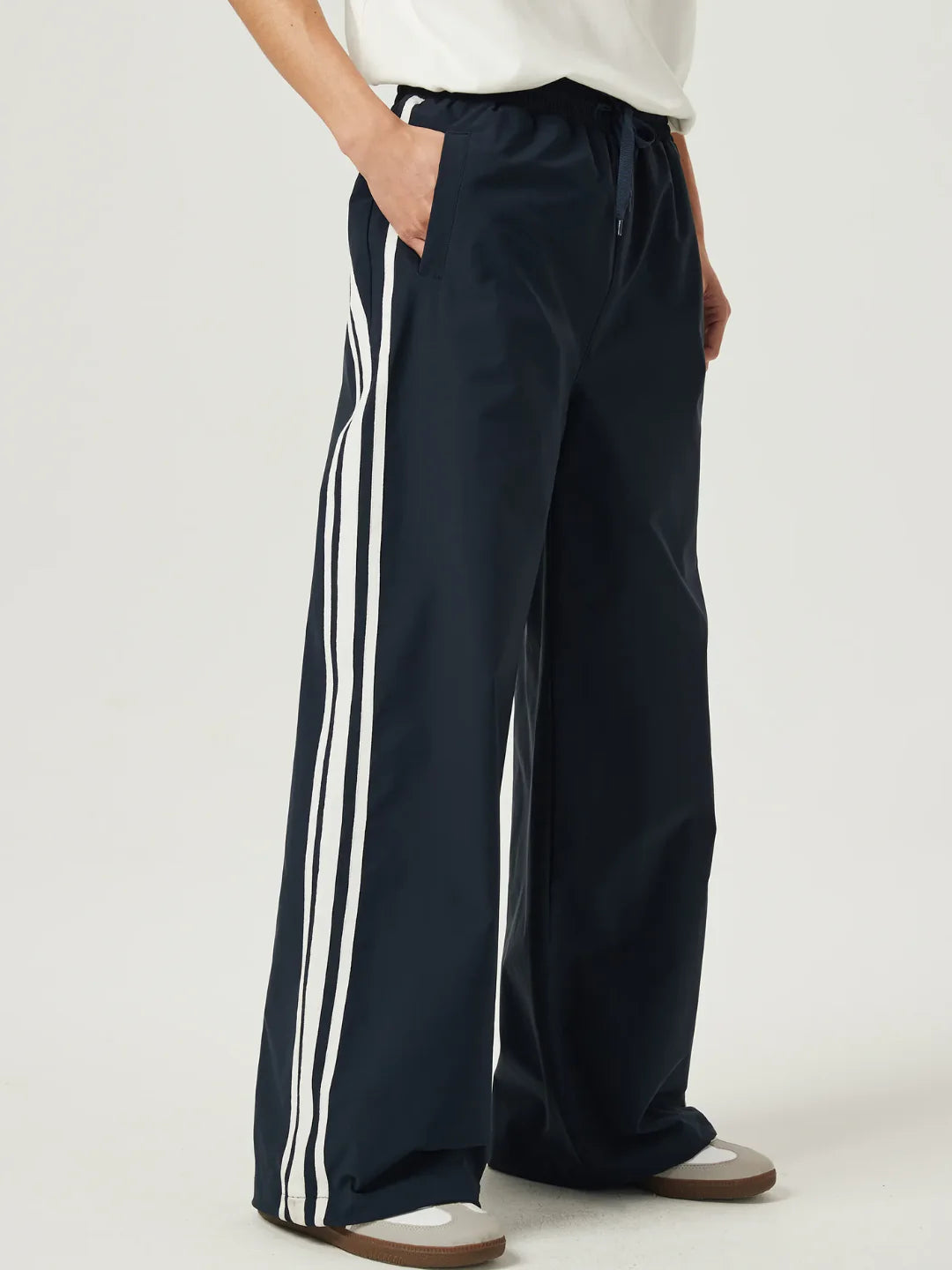 Navy pants with white stripes worn by a person on a light gray background