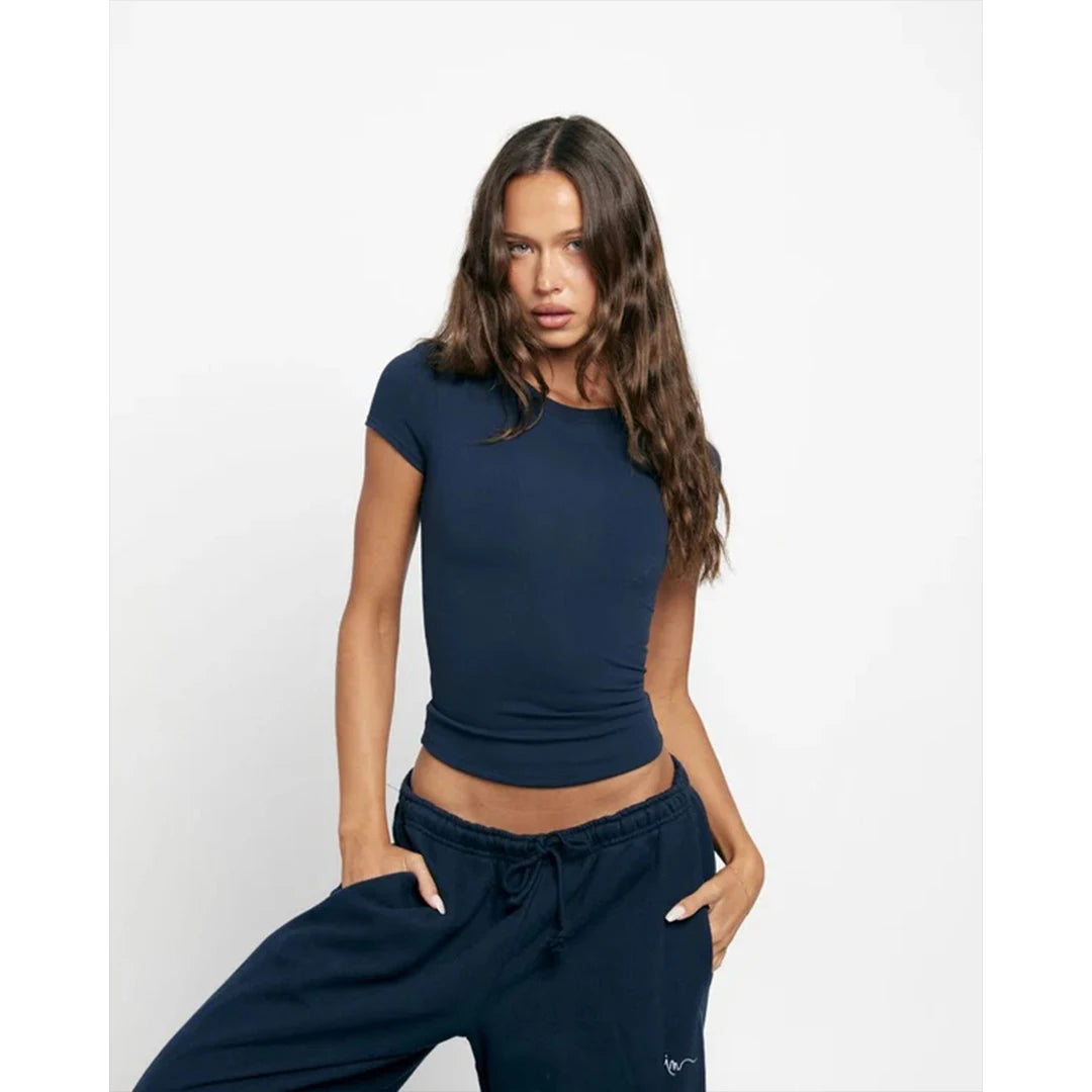 Woman wearing a navy blue crop top and sweatpants on a white background