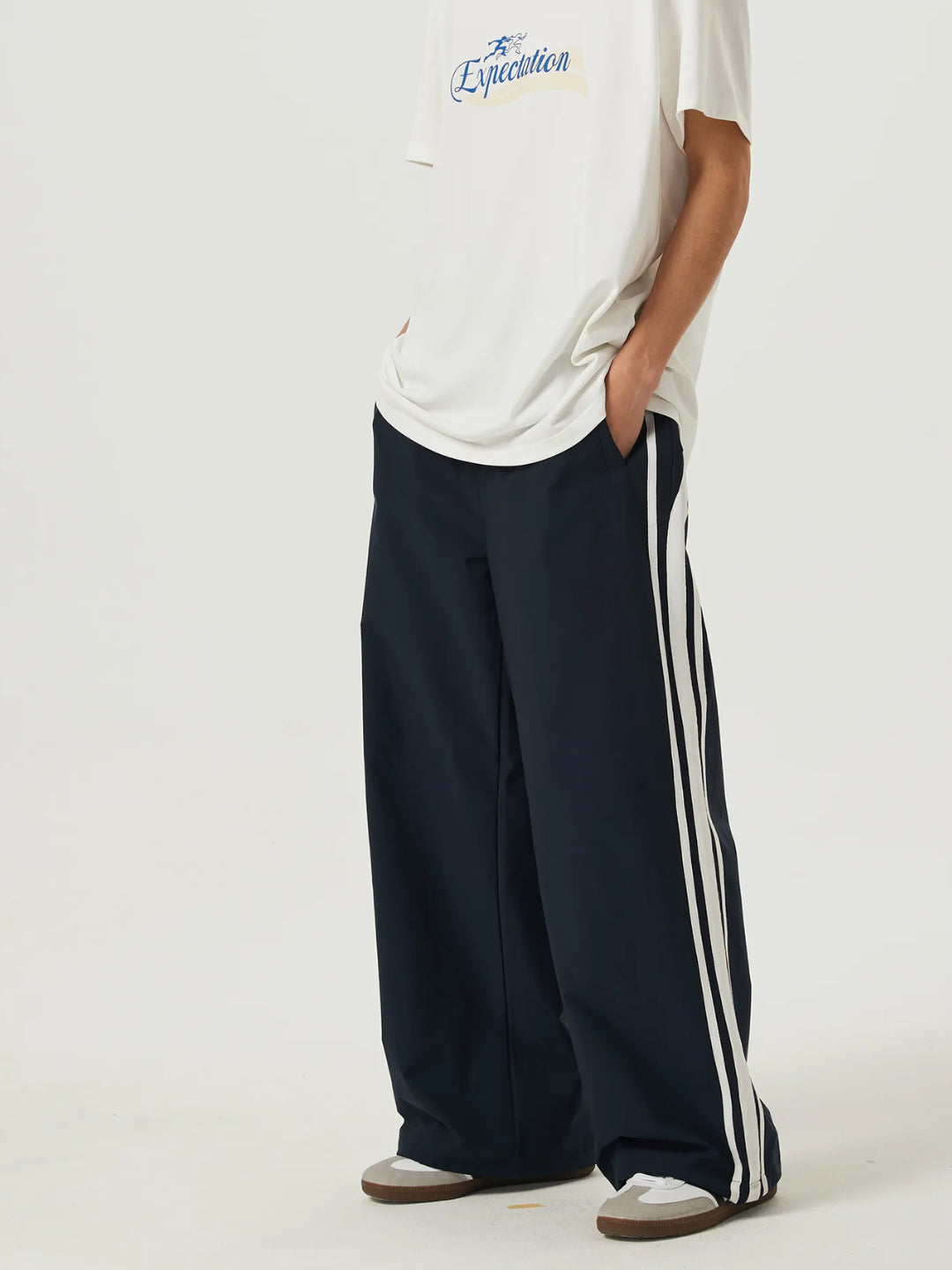 navy blue race track pants with white stripes on the side and an elasticated waistband with a drawstring