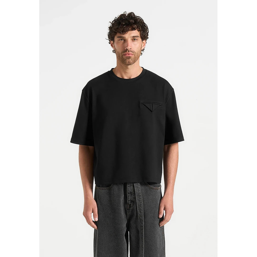 Man wearing a black t-shirt with a small logo on a white background