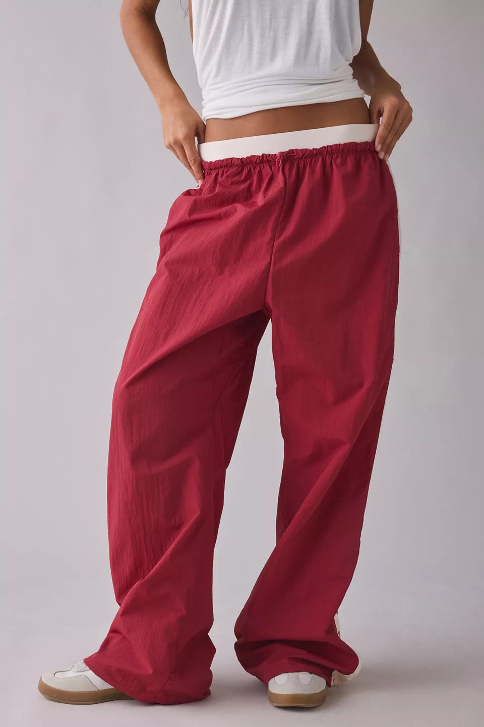Person wearing red wide-leg pants and a white top on a plain background
