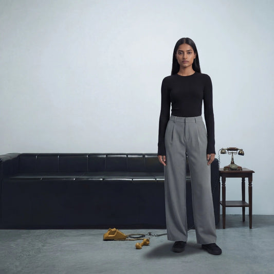 Woman standing in a minimalistic room with a black sofa and small table.