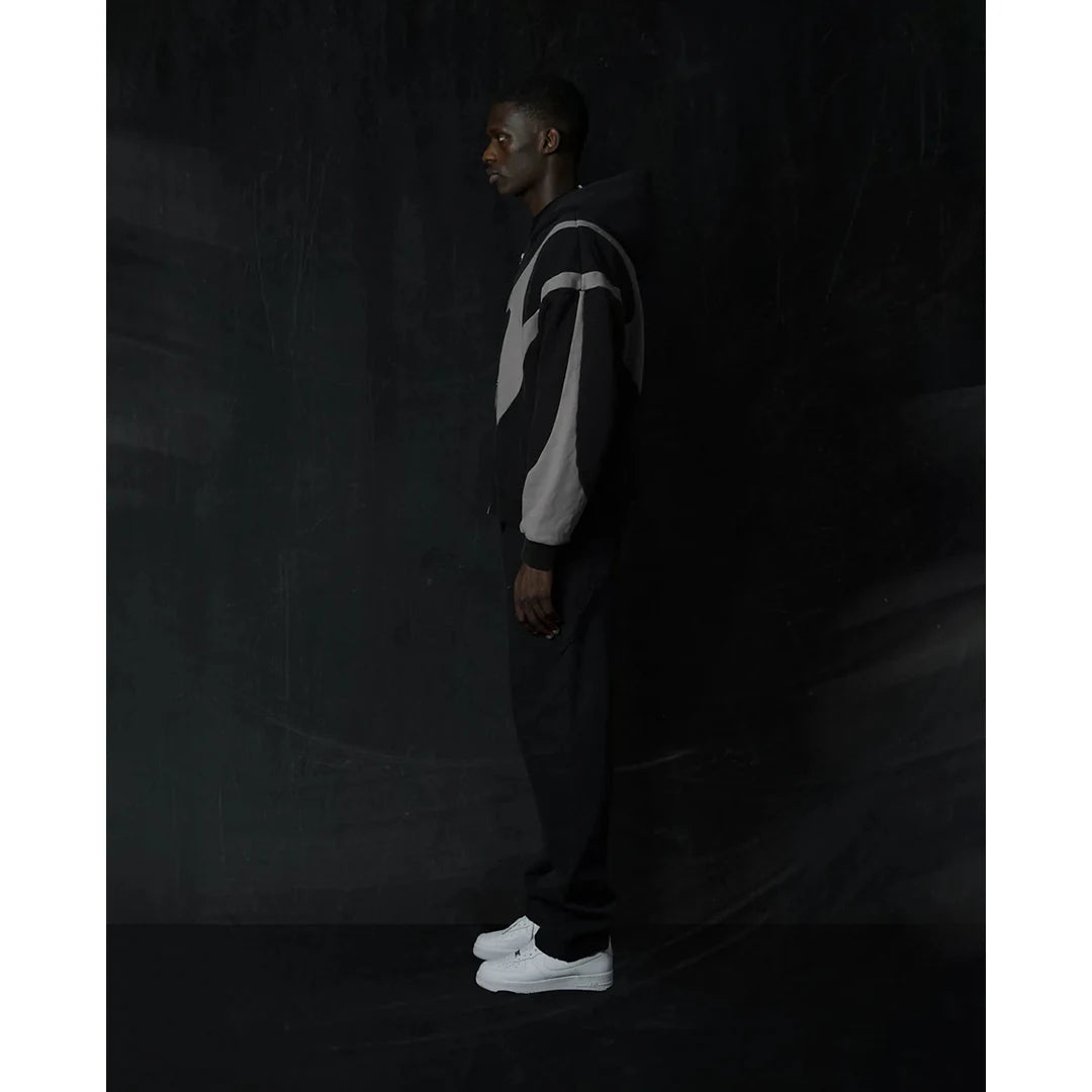 Person wearing a black and white striped hoodie and pants against a dark background