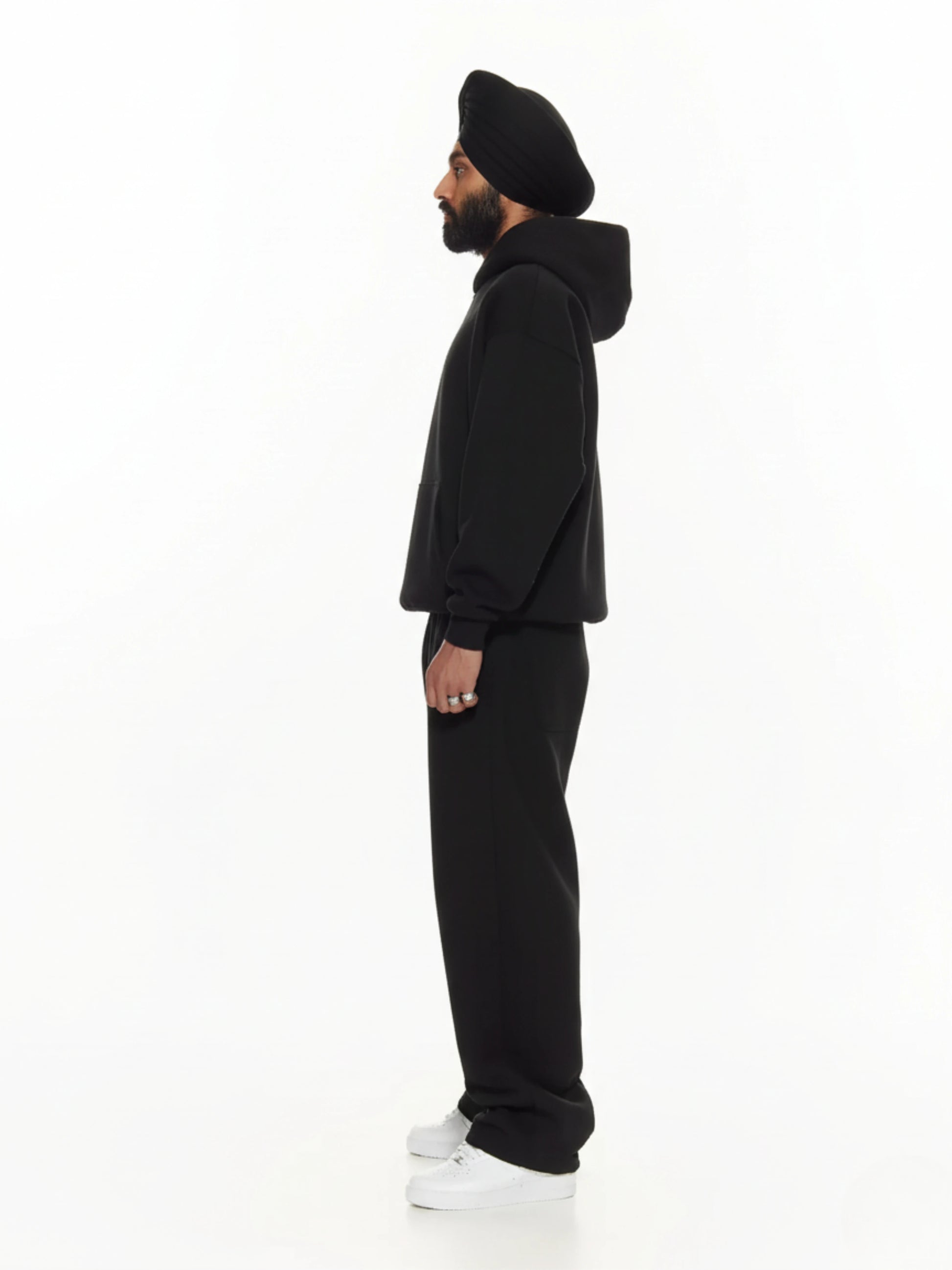Person wearing a black hoodie and pants on a white background