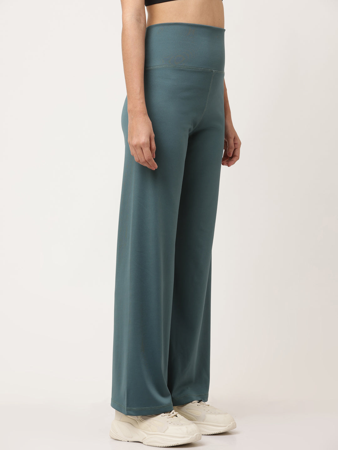 A model wearing green flared high-rise full-length yoga pants with a solid pattern.