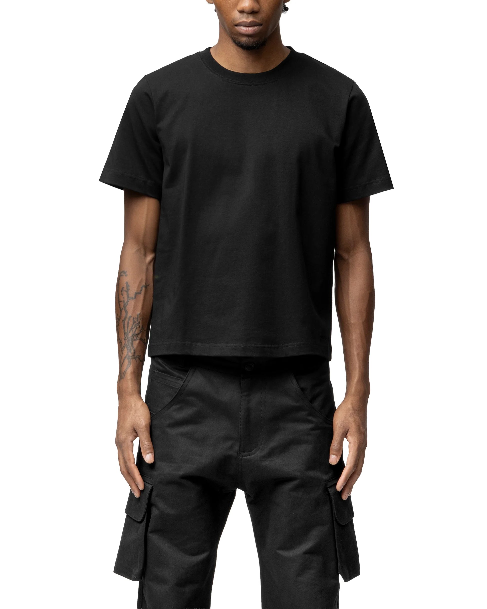 Person wearing a black t-shirt and black cargo pants on a white background