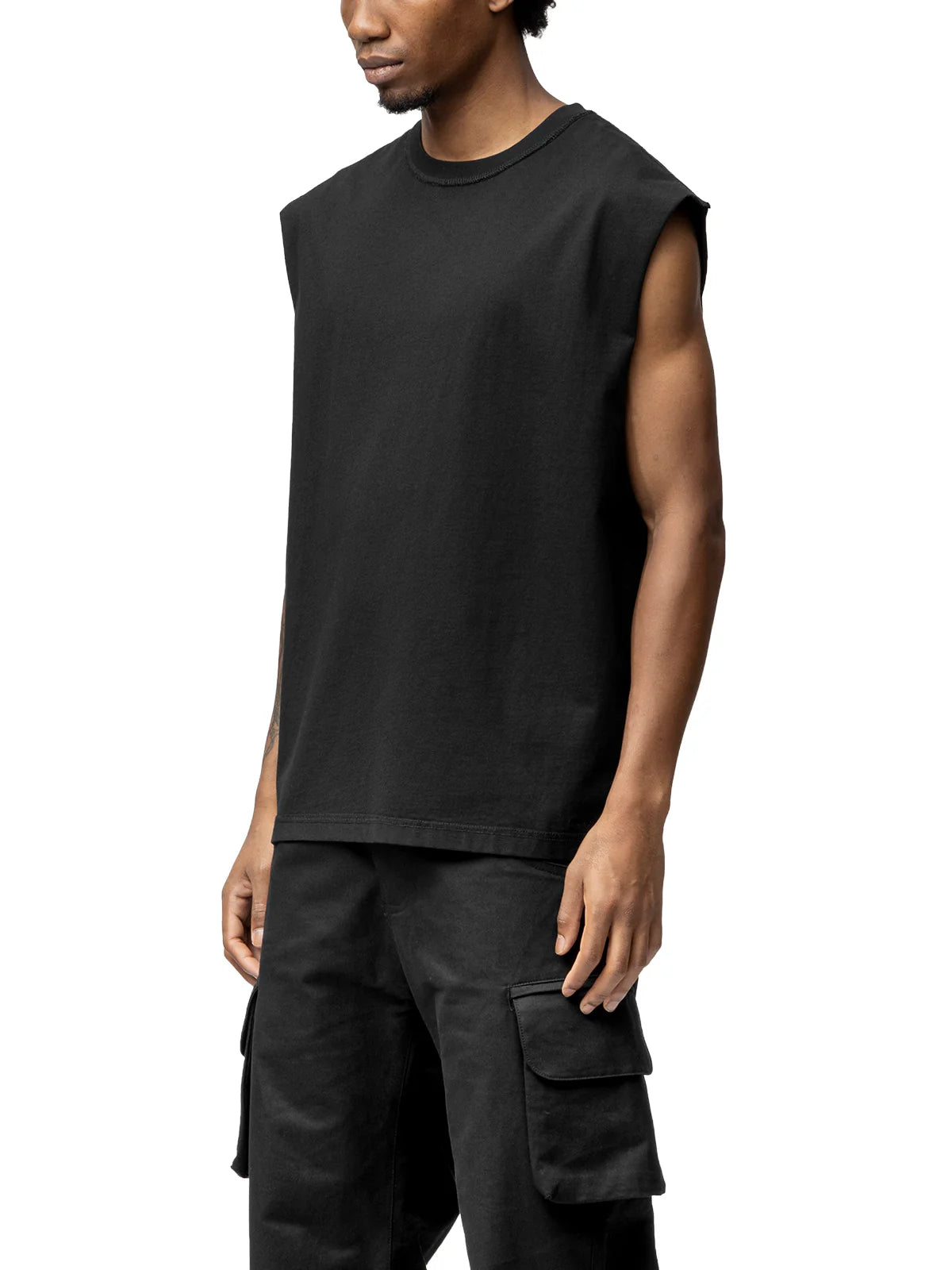 Person wearing a black sleeveless shirt and cargo pants on a white background