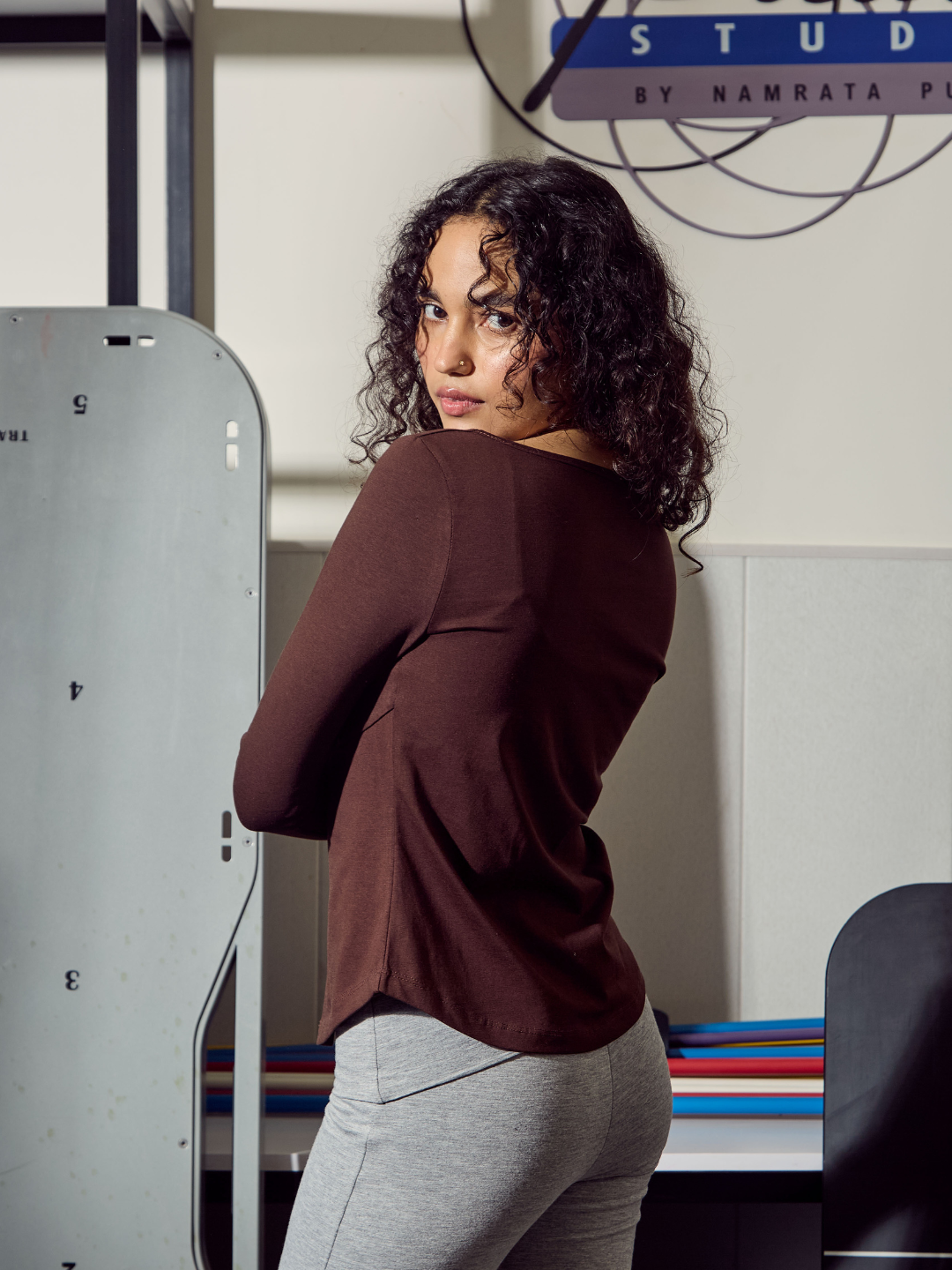 Woman in a brown top and grey pants standing in front of a whiteboard with text on it.