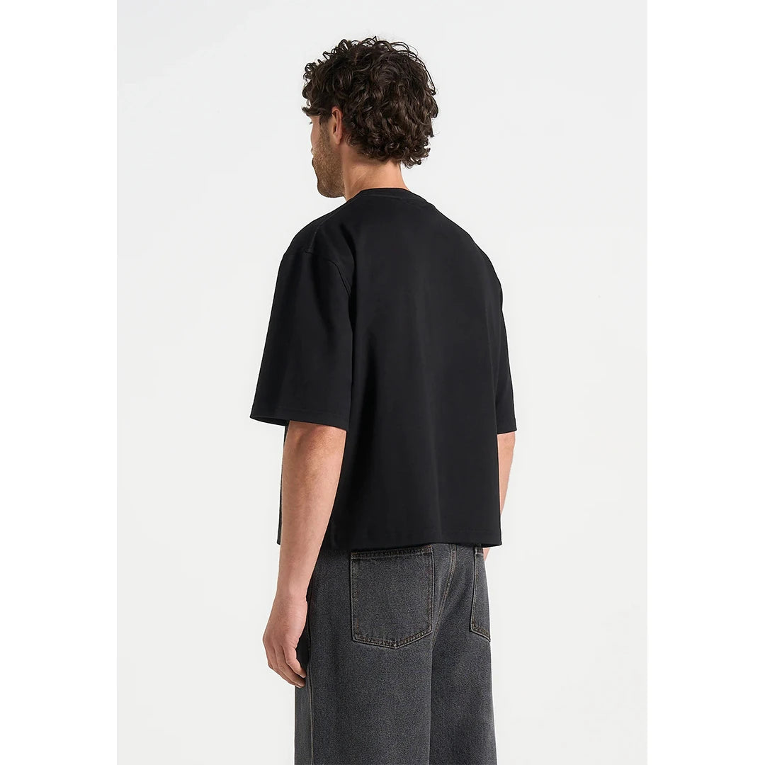 Person wearing a black t-shirt and gray pants on a white background