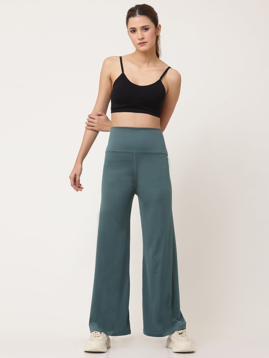 A model wearing green flared high-rise full-length yoga pants with a solid pattern.