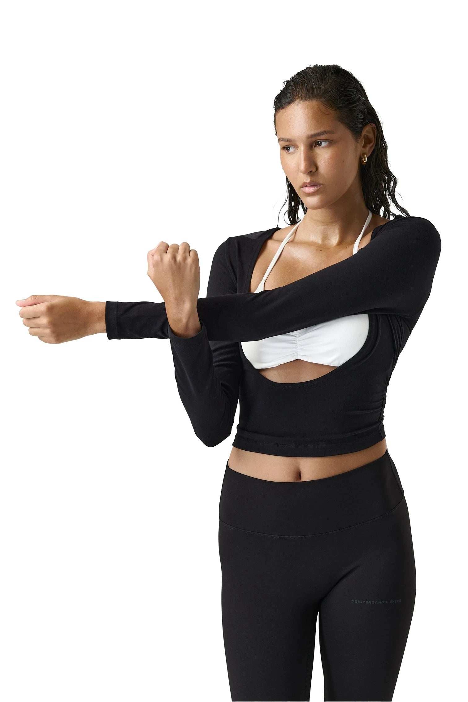 Woman wearing a black long-sleeve crop top and black leggings on a white background