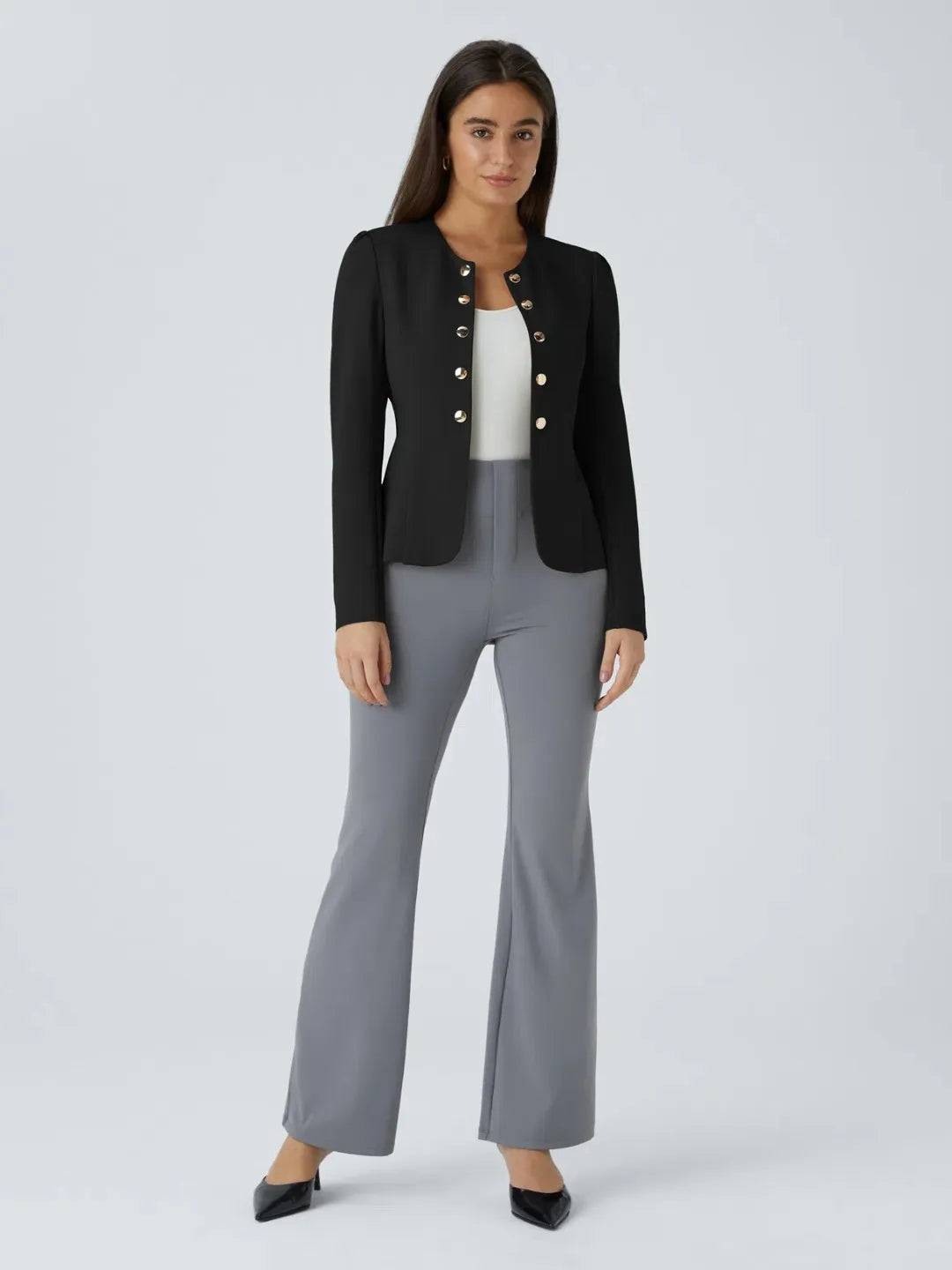 Woman wearing a black buisness jacket with gold buttons on a light gray background