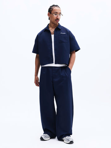 Person wearing a navy blue outfit with a white shirt underneath on a white background