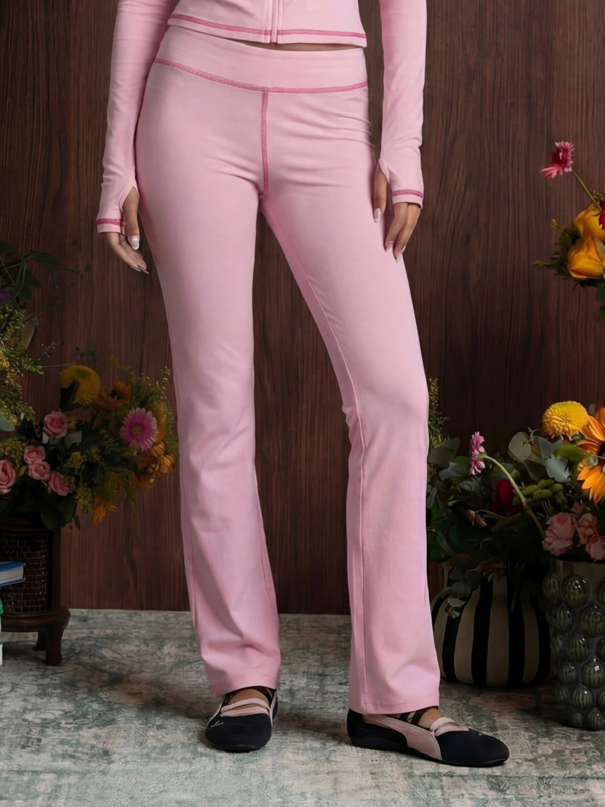 Person wearing a pink outfit with a wooden background and floral decorations