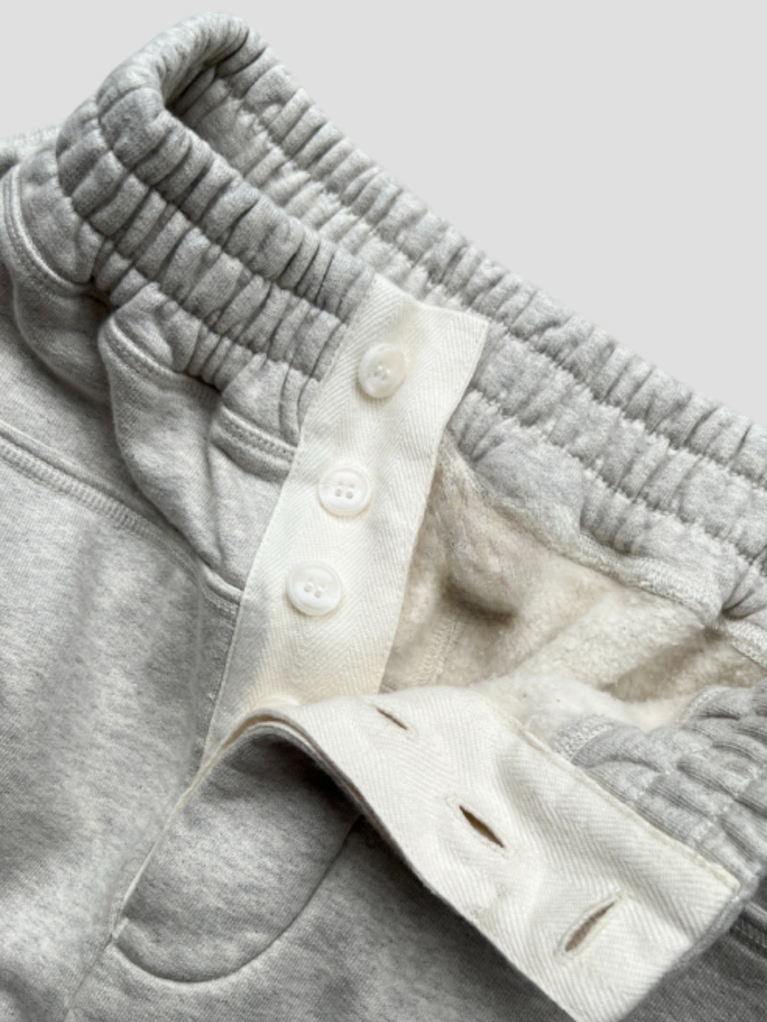  Sweatpant include a buttoned front fly, functional front and back pockets, and subtle construction details that add structure without compromising comfort. 