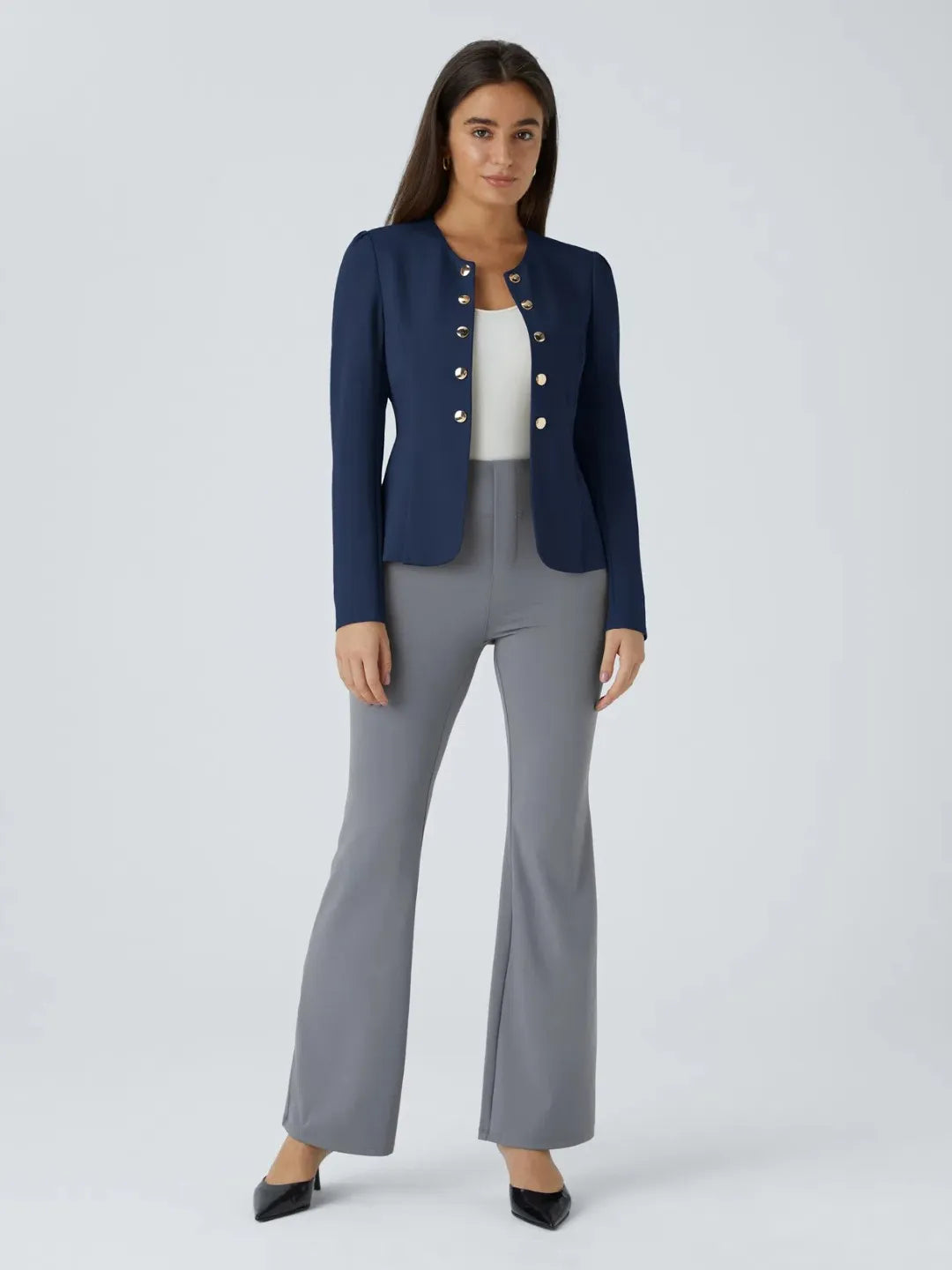 Woman wearing a blue buisness jacket with gold buttons on a light gray background