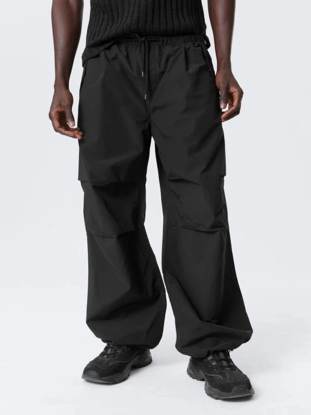 Person wearing black cargo pants on a white background