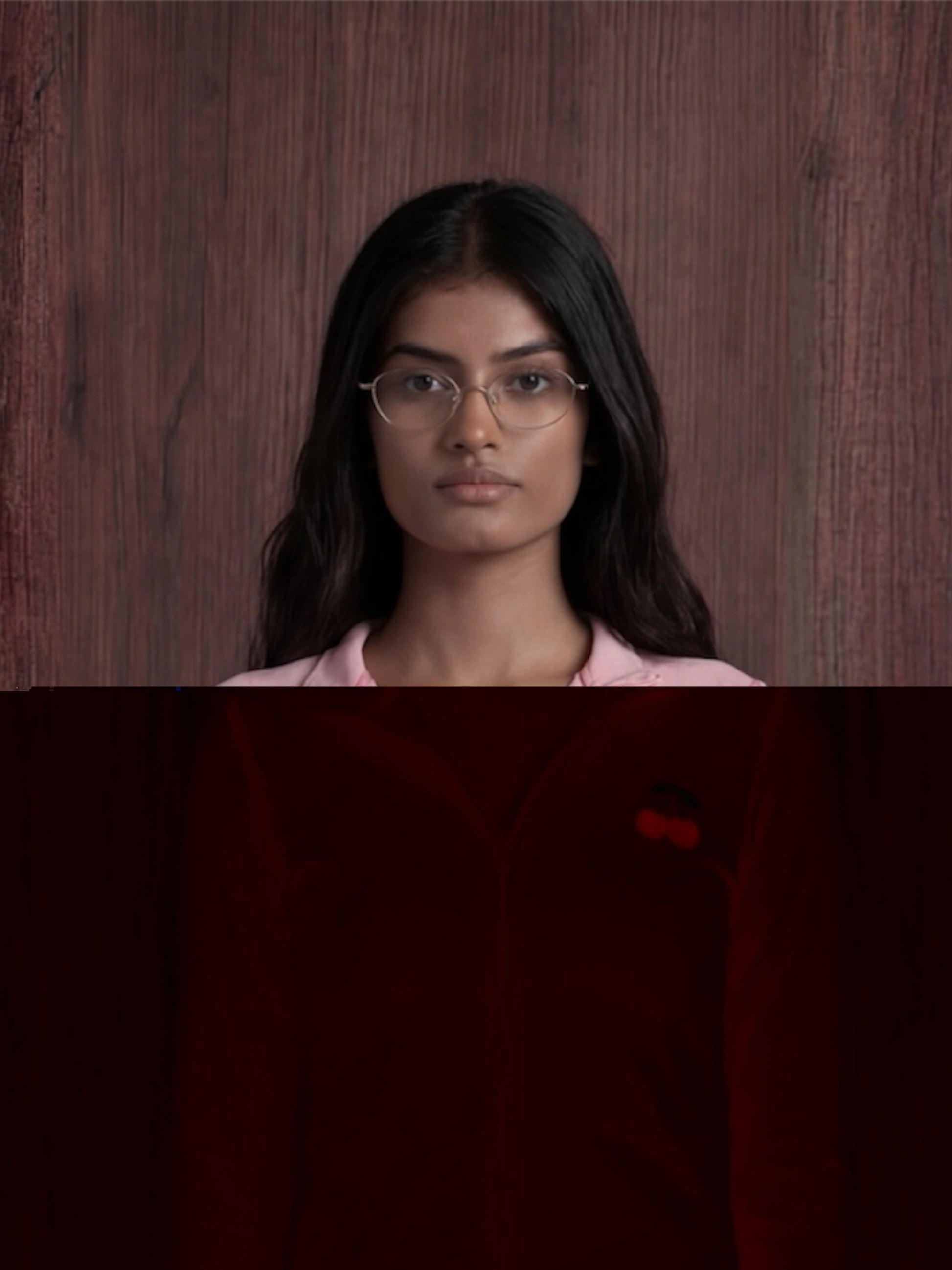 Woman wearing glasses and a pink shirt against a wooden background