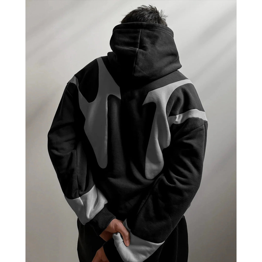 Person wearing a black and gray hoodie with a white stripe on a plain background