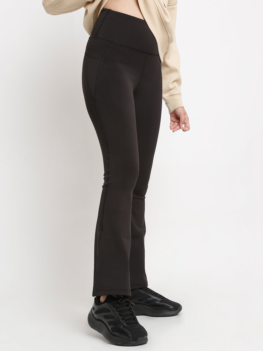 A person wearing black flare high-waisted essential pants with pockets, paired with a beige top and black shoes.