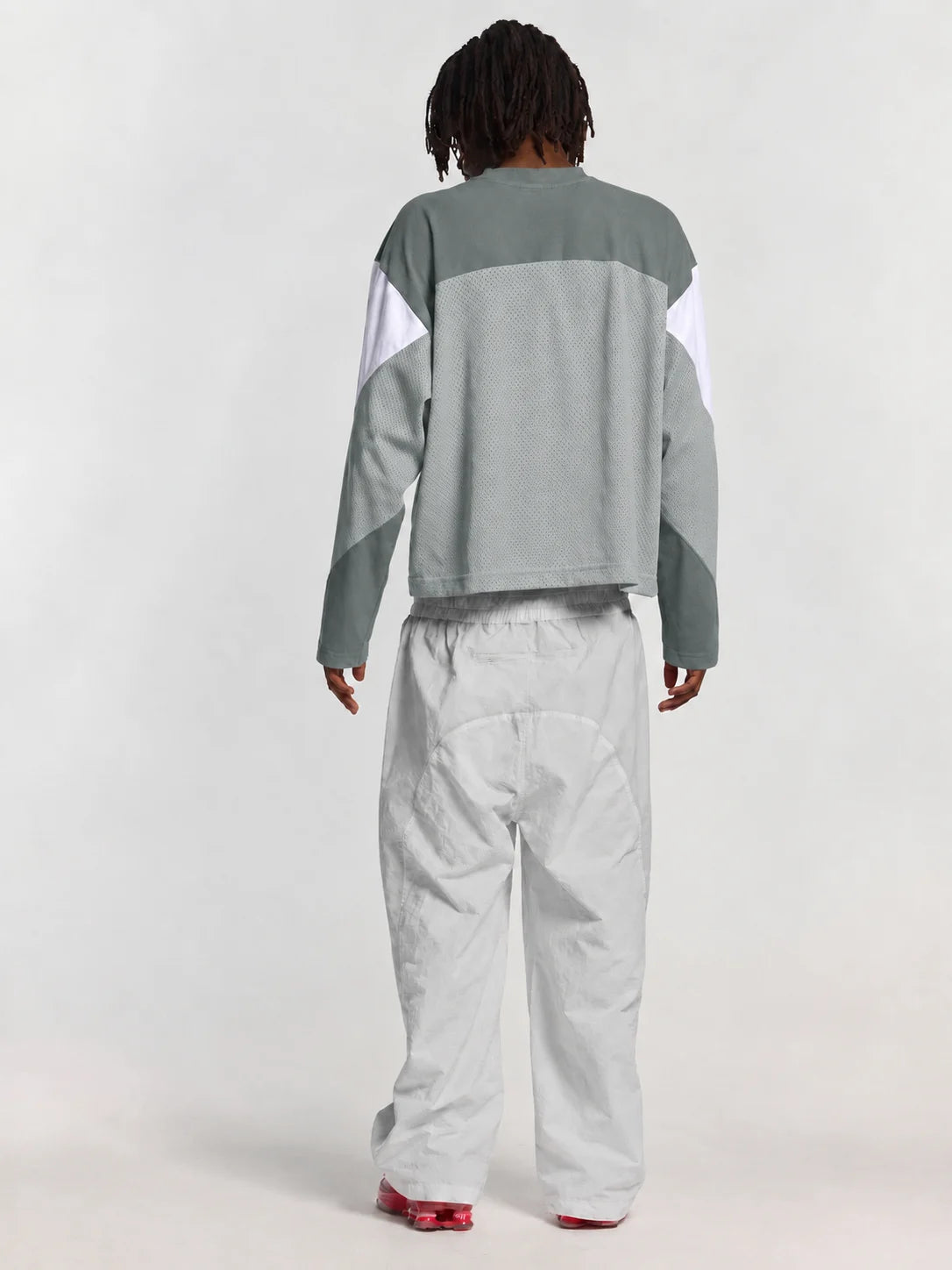 A person wearing a color-blocked long-sleeve top in grey and white, paired with light grey pants