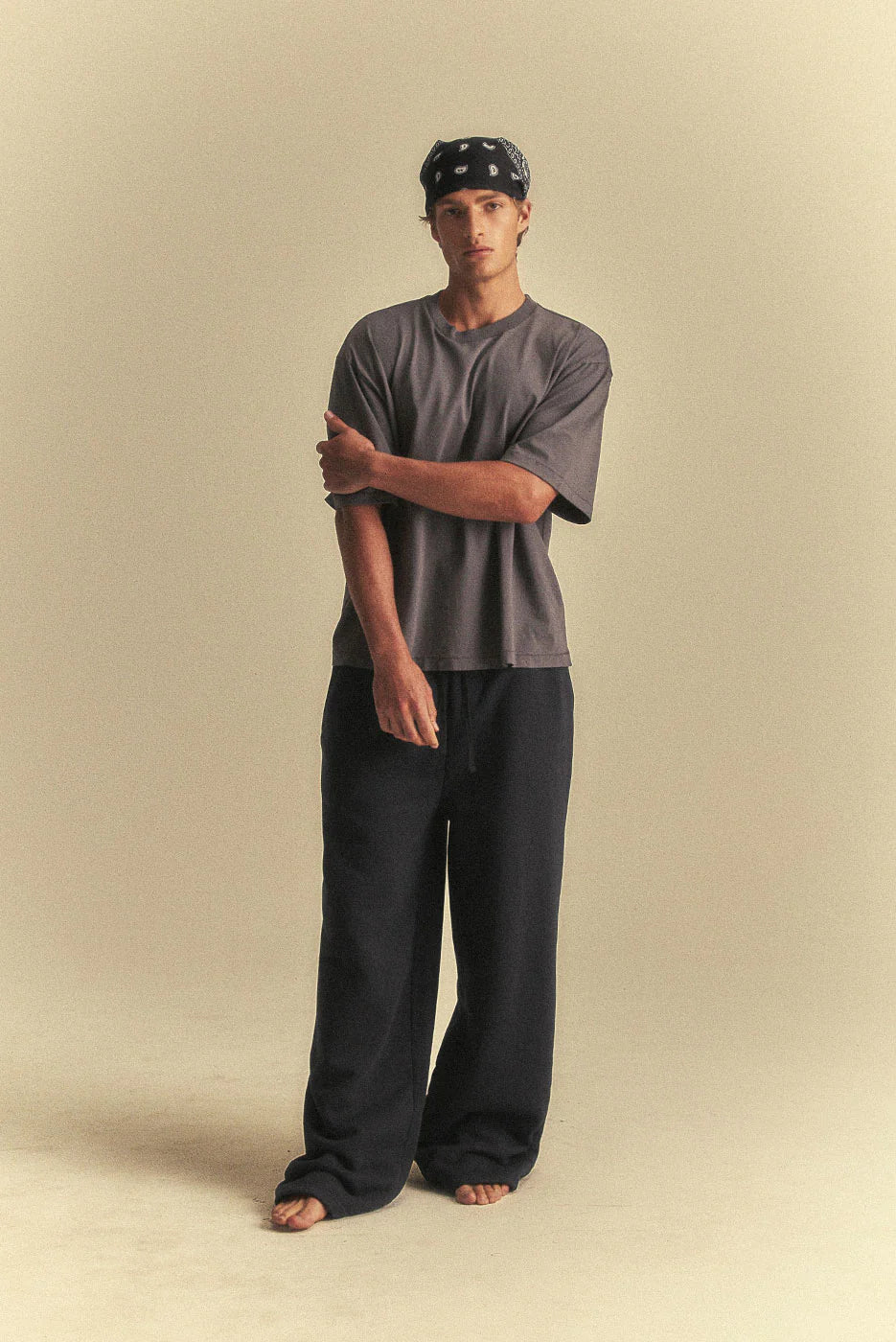 Person wearing a grey t-shirt and black pants on a beige background