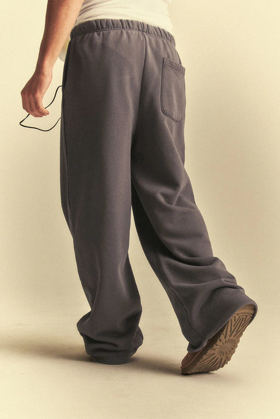 Person wearing grey sweatpants on a beige background