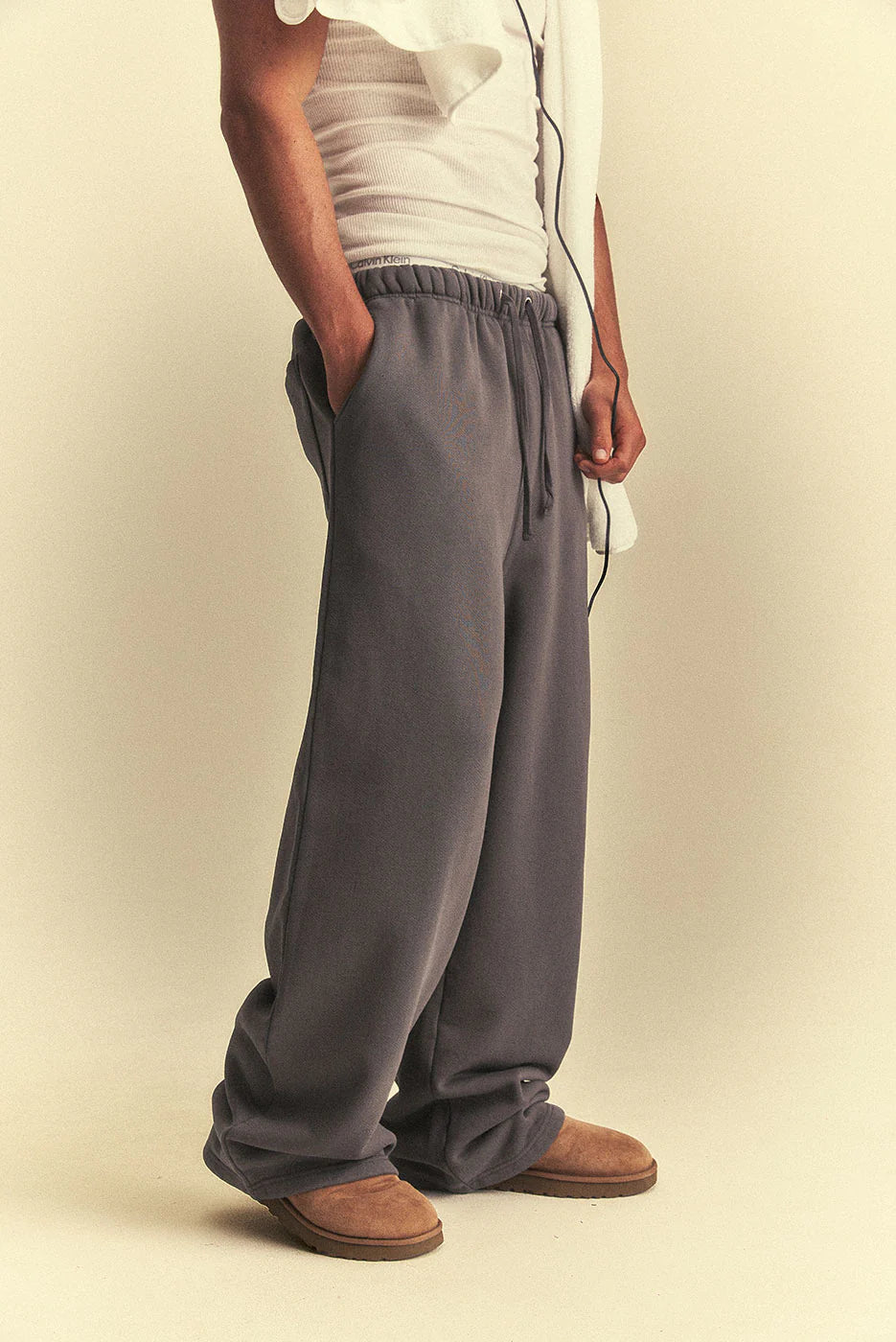 Person wearing grey wide-leg pants and brown shoes on a beige background