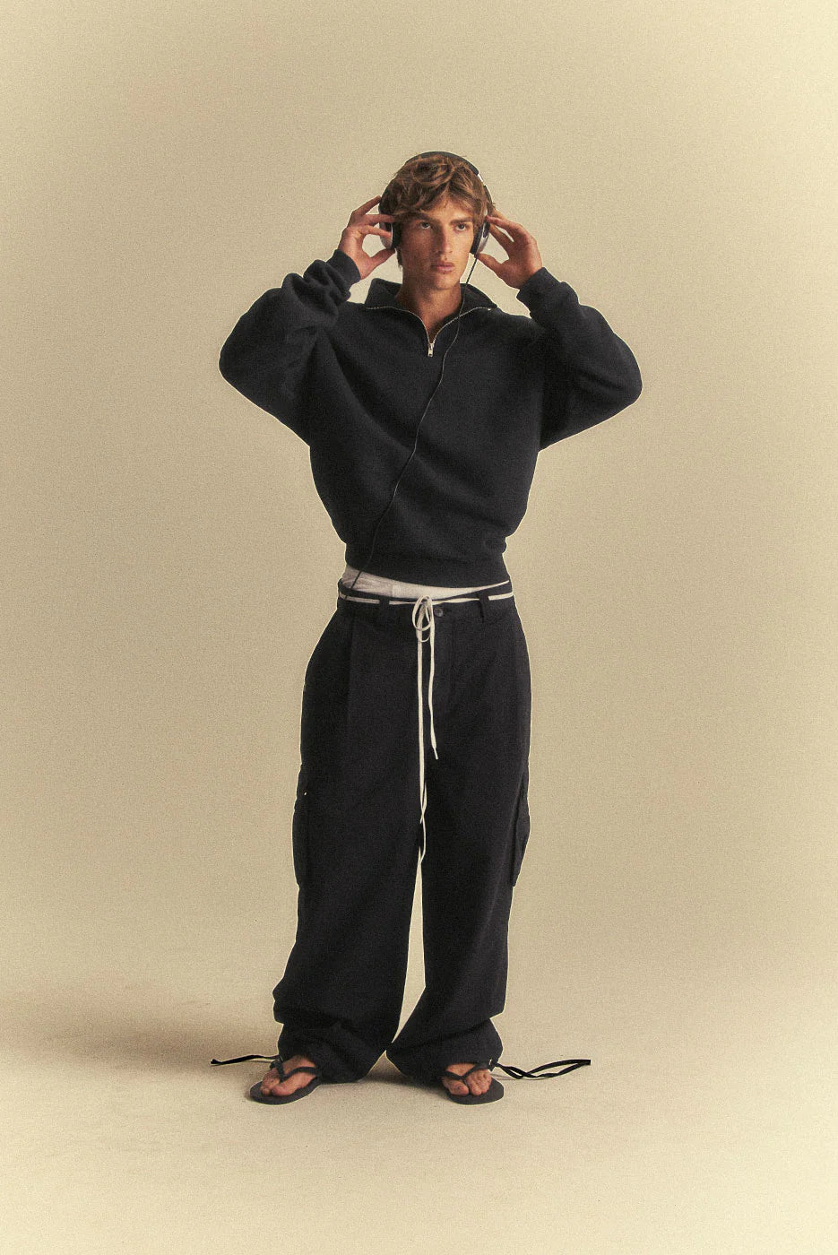 Person wearing a black tracksuit on a beige background