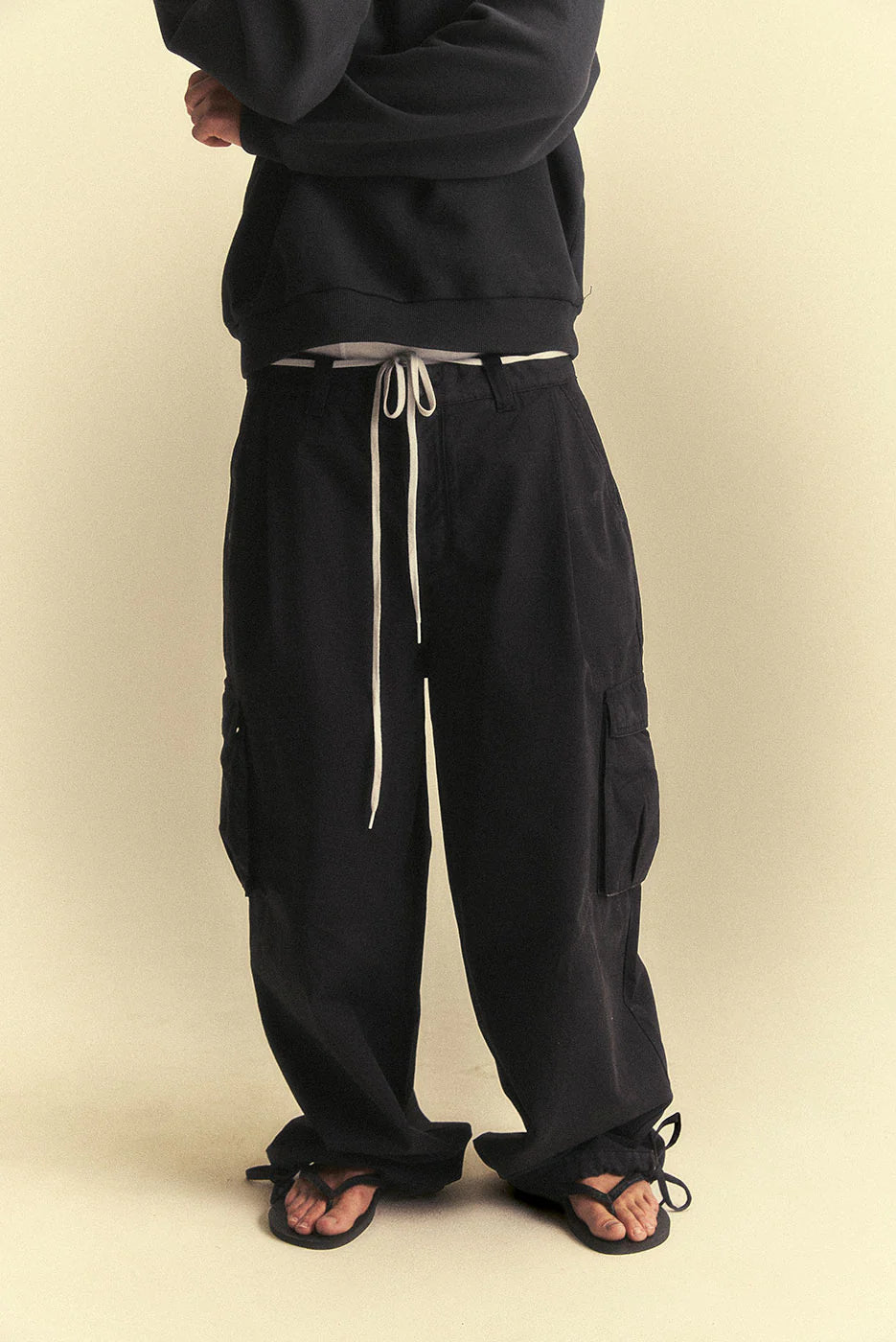 Person wearing black cargo pants with a beige background