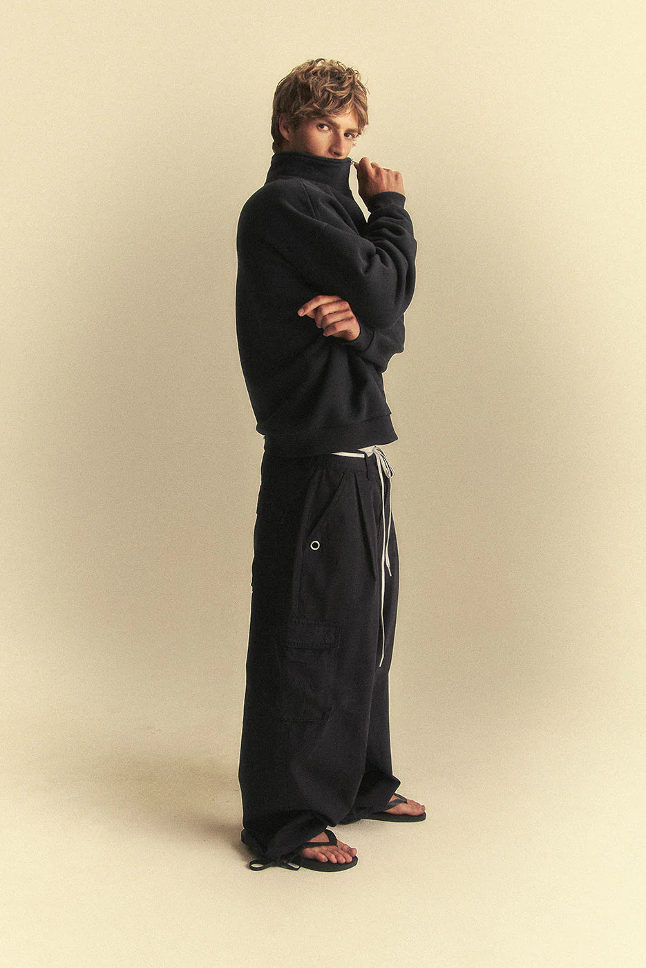 Person wearing a black outfit on a beige background
