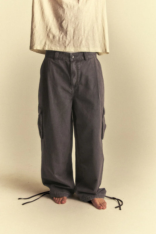 Person wearing dark grey cargo pants on a beige background