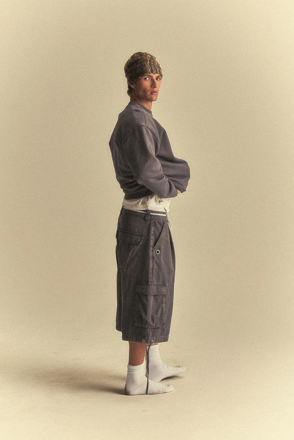 Person wearing a grey sweater and dark pants on a beige background