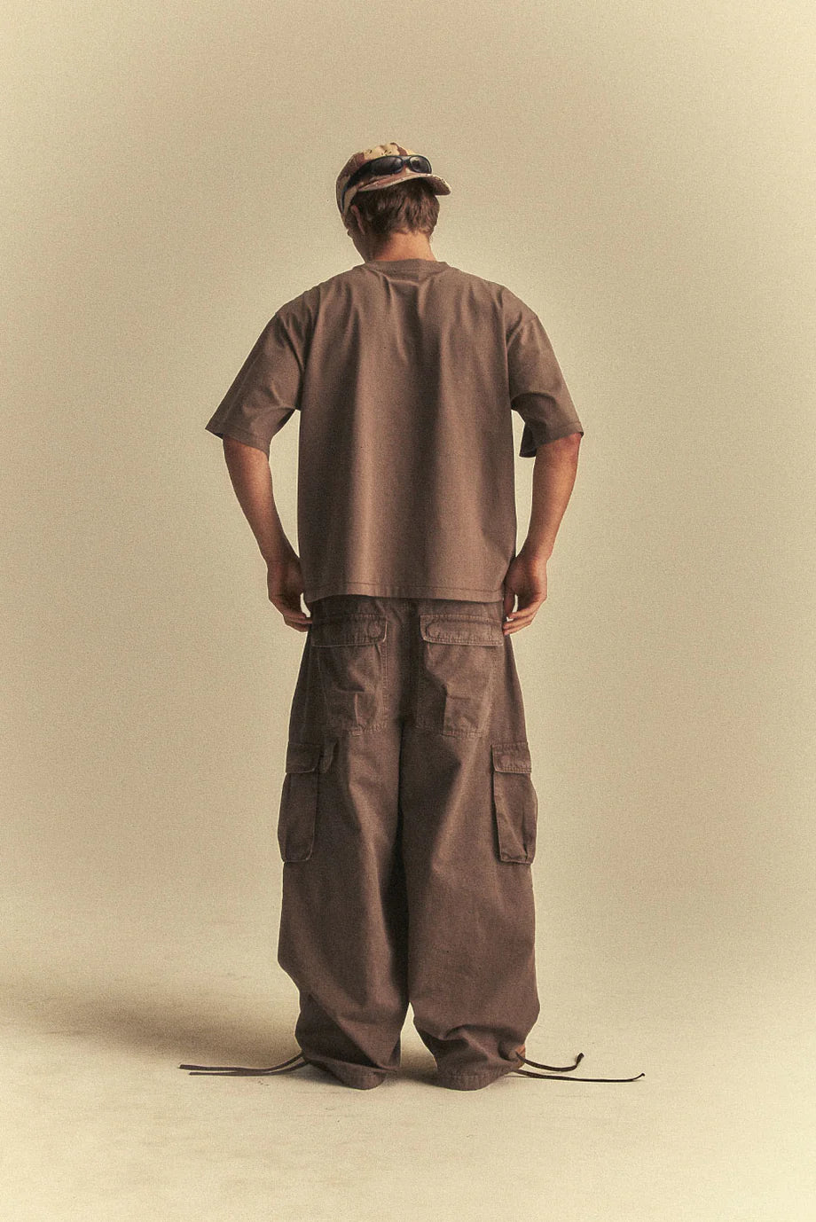 Person wearing a brown outfit standing against a beige background