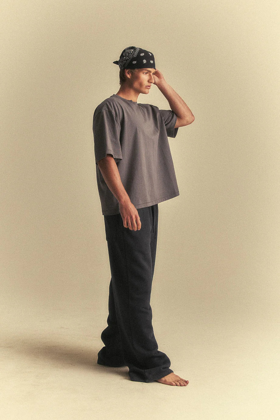 Person wearing a grey oversized t-shirt and black pants on a beige background