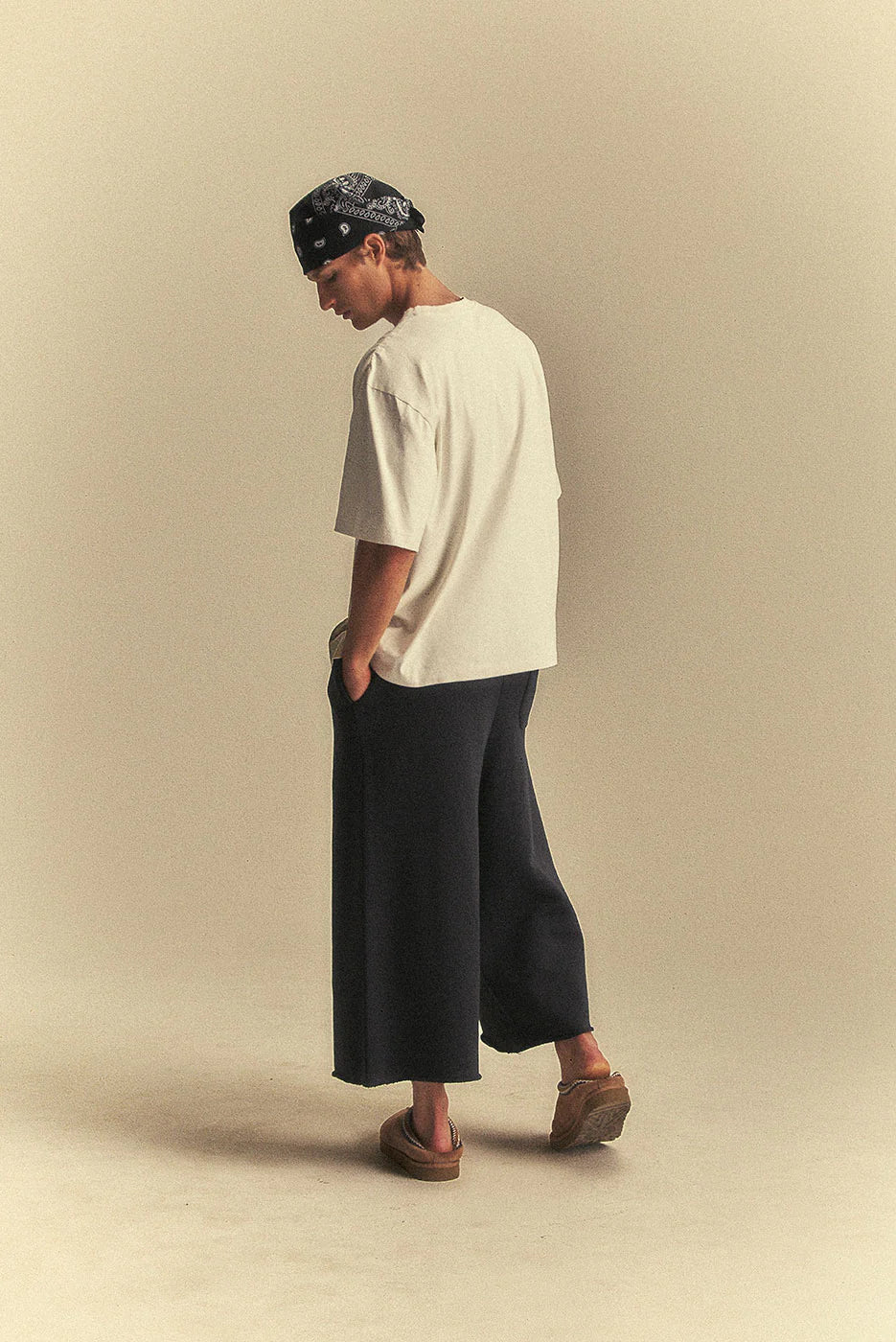 Person wearing a white t-shirt and black wide-leg pants on a beige background