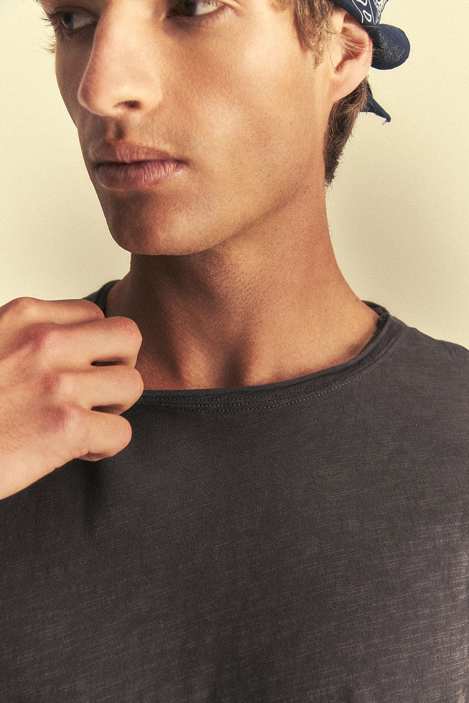 Man wearing a dark grey t-shirt and cap on a beige background