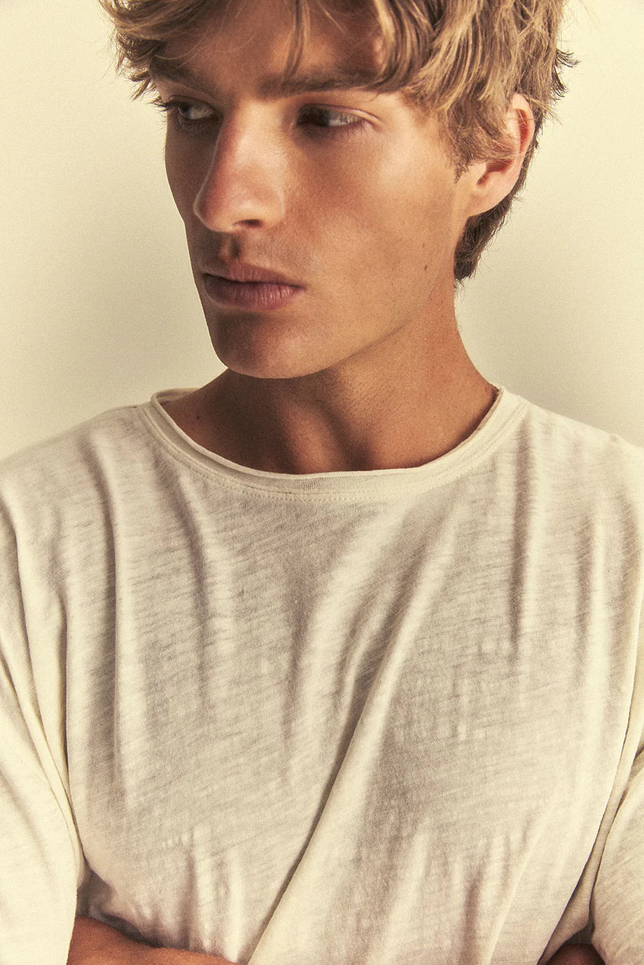 Man wearing a light grey t-shirt against a neutral background